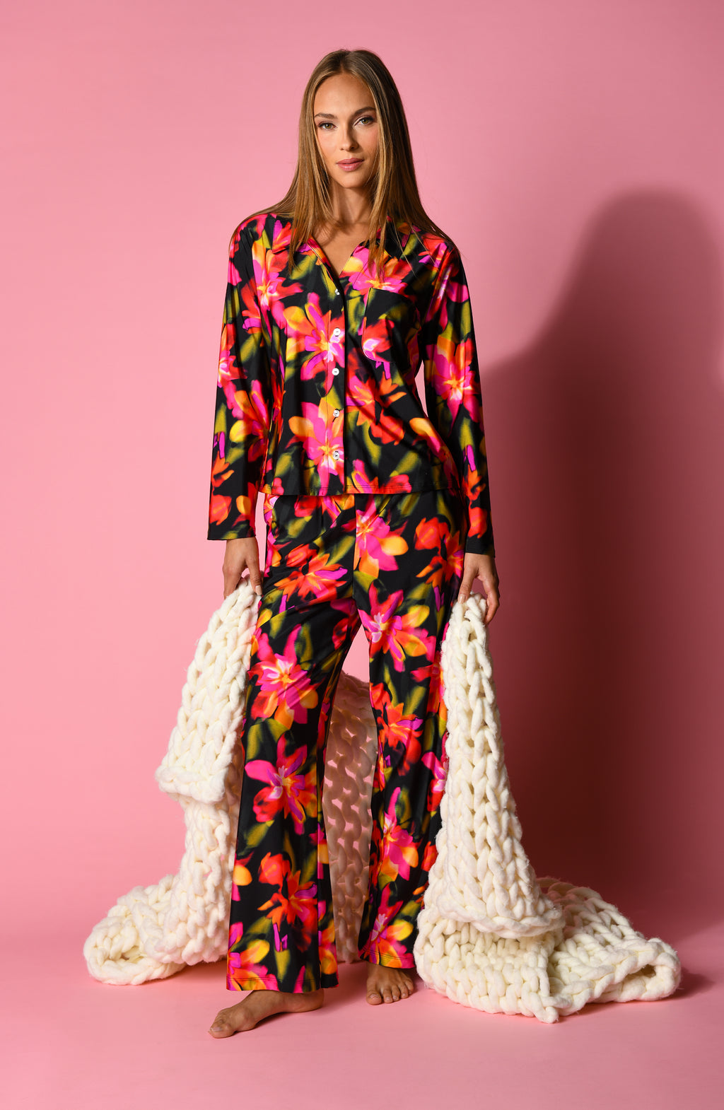Woman wearing a colorful floral pajama set on a pink background