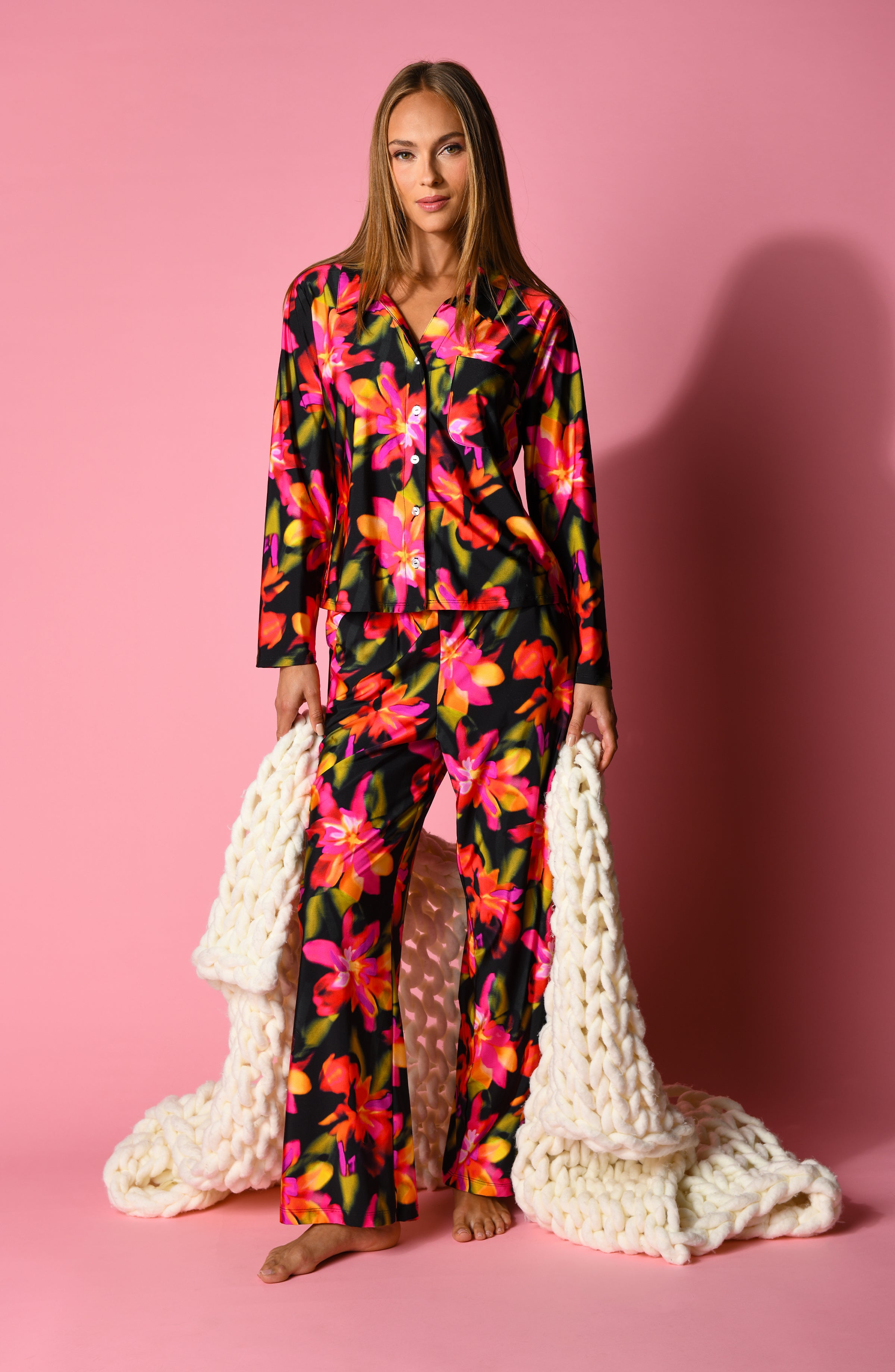 Woman wearing a colorful floral pajama set on a pink background