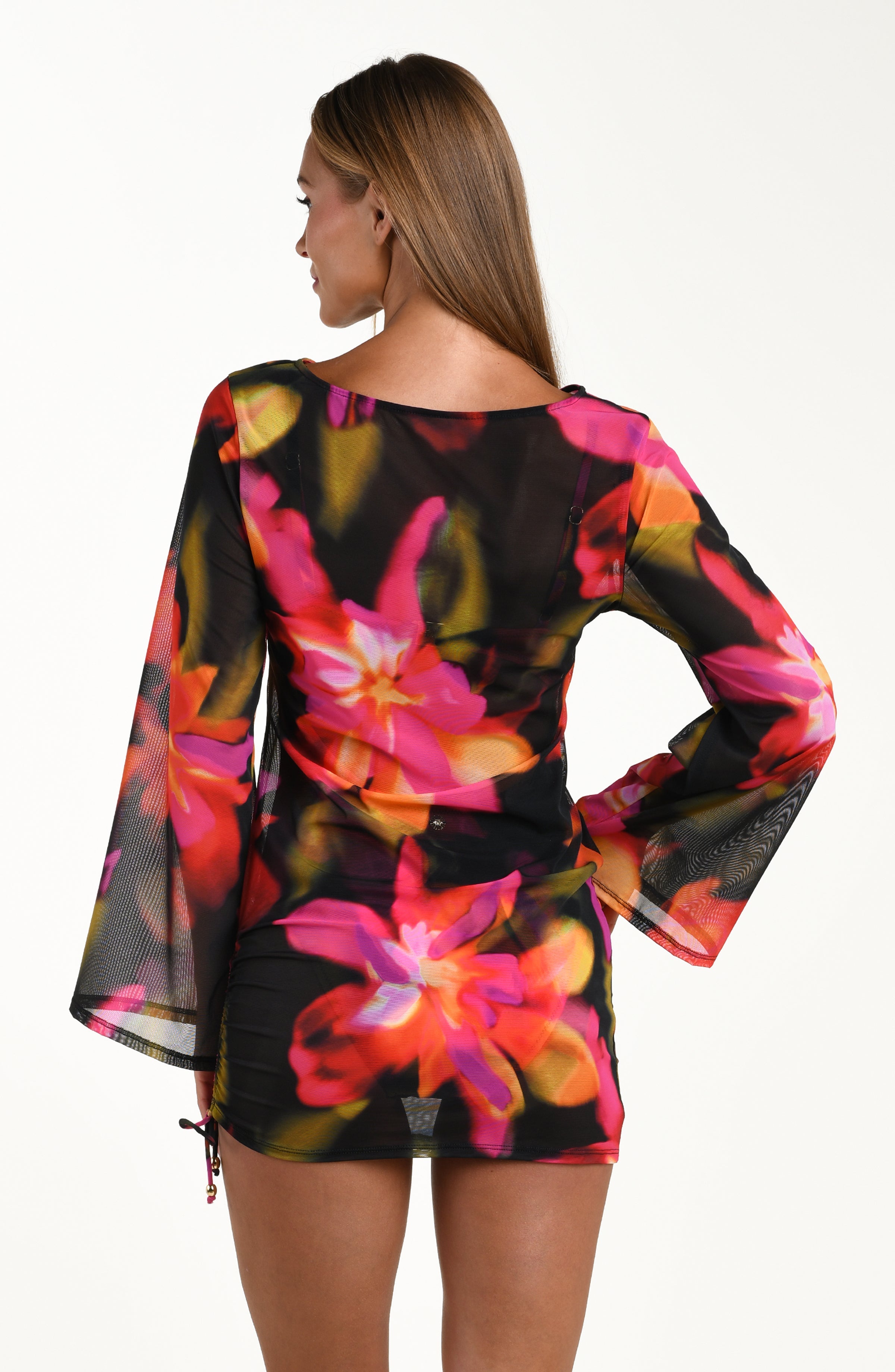 Back image of model wearing a sheer long-sleeve tunic cover-up with adjustable side ties in a multicolored floral print.