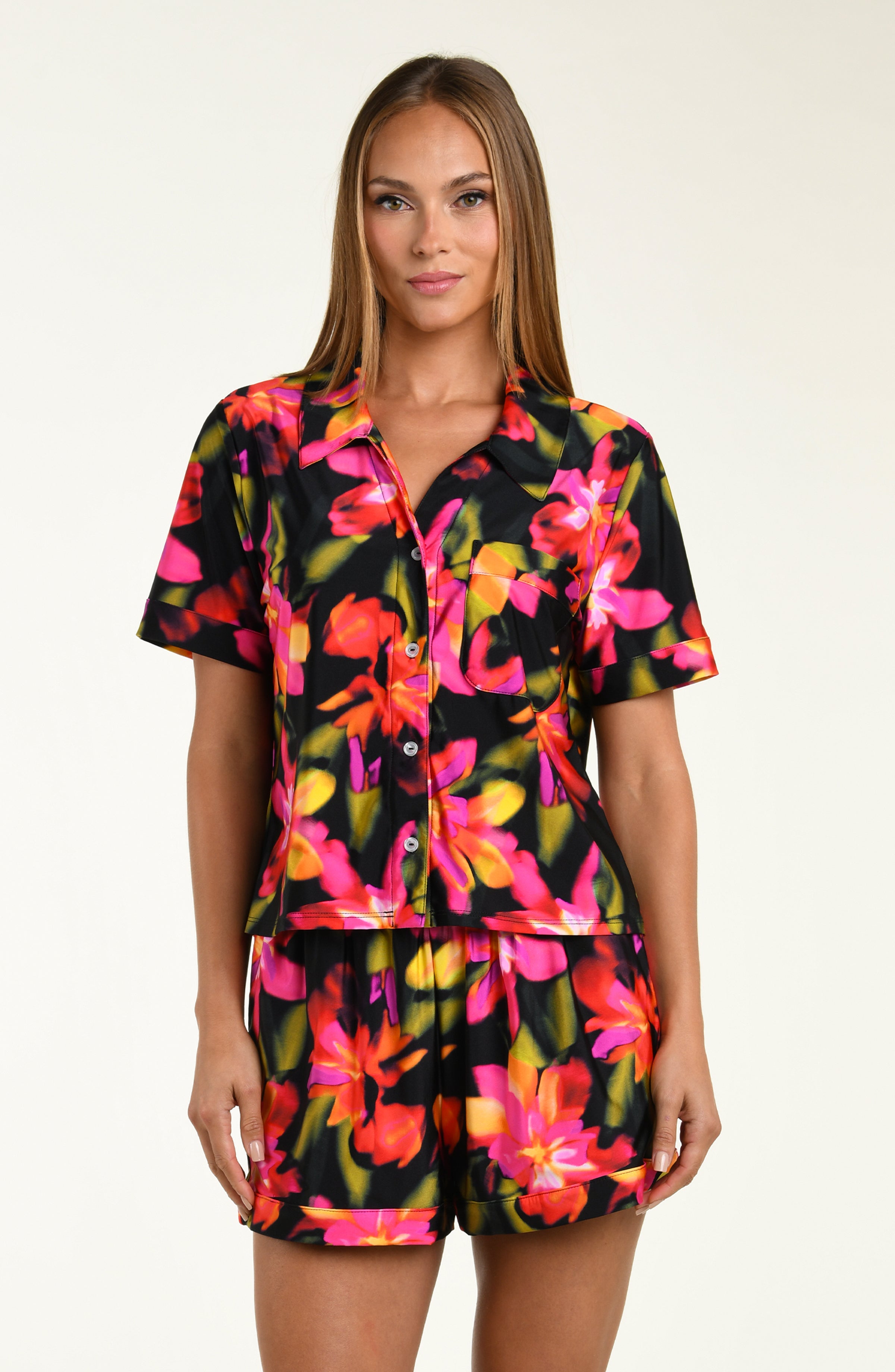 Woman wearing a colorful floral shirt and short pajama set on a white background