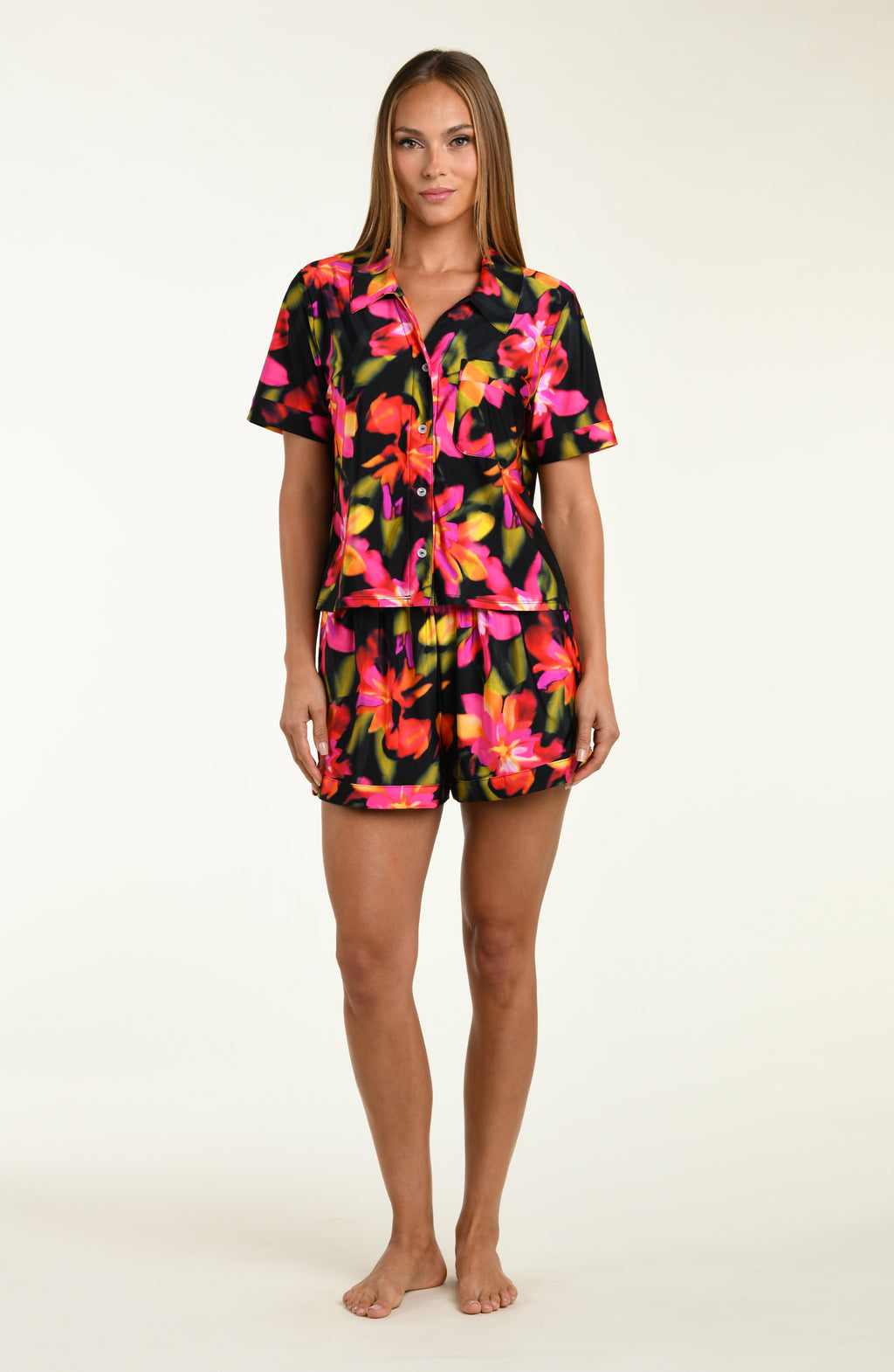 Woman wearing a colorful floral shirt and short pajama set on a white background