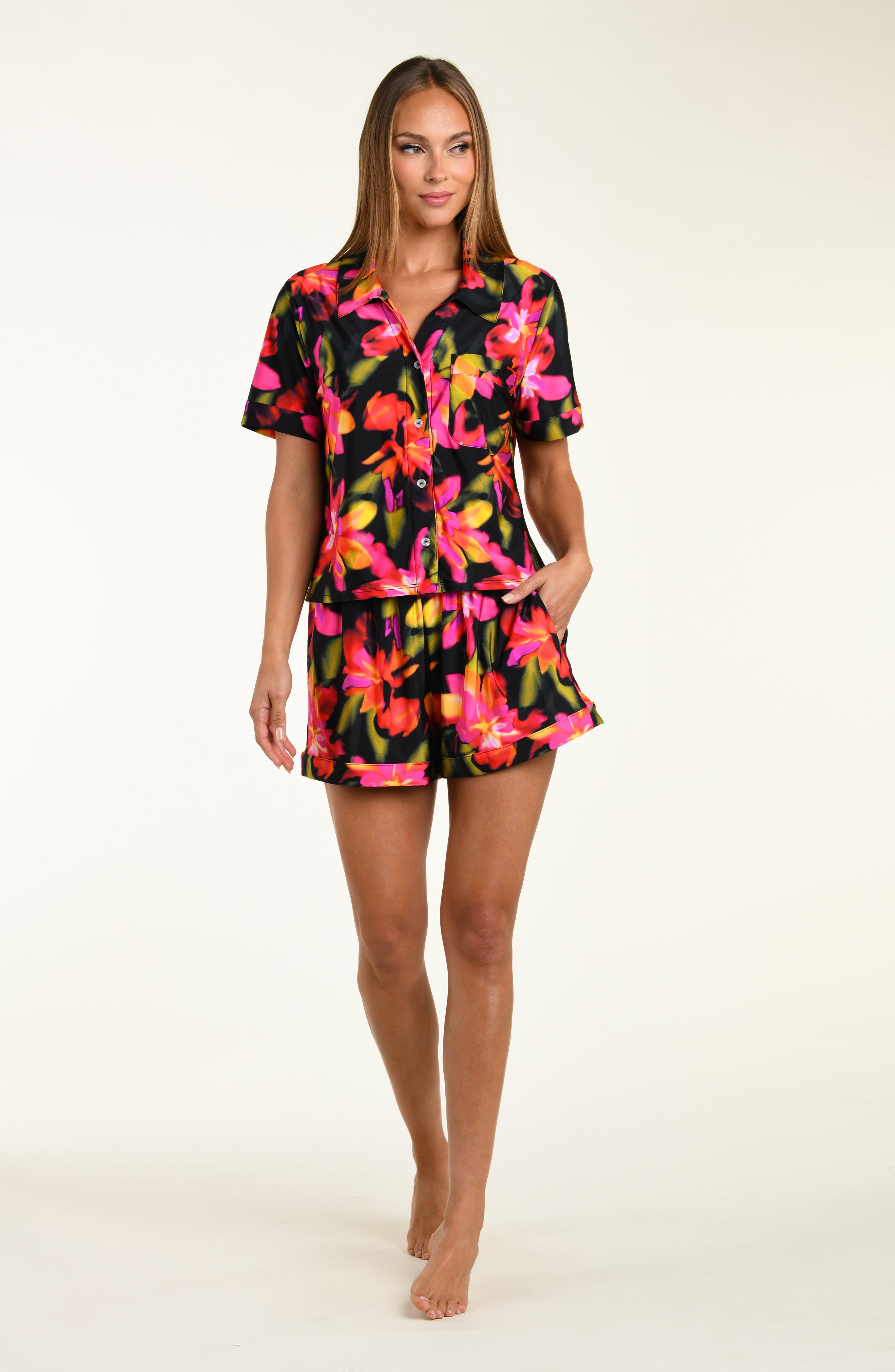 Woman wearing a colorful floral shirt and short pajama set on a white background