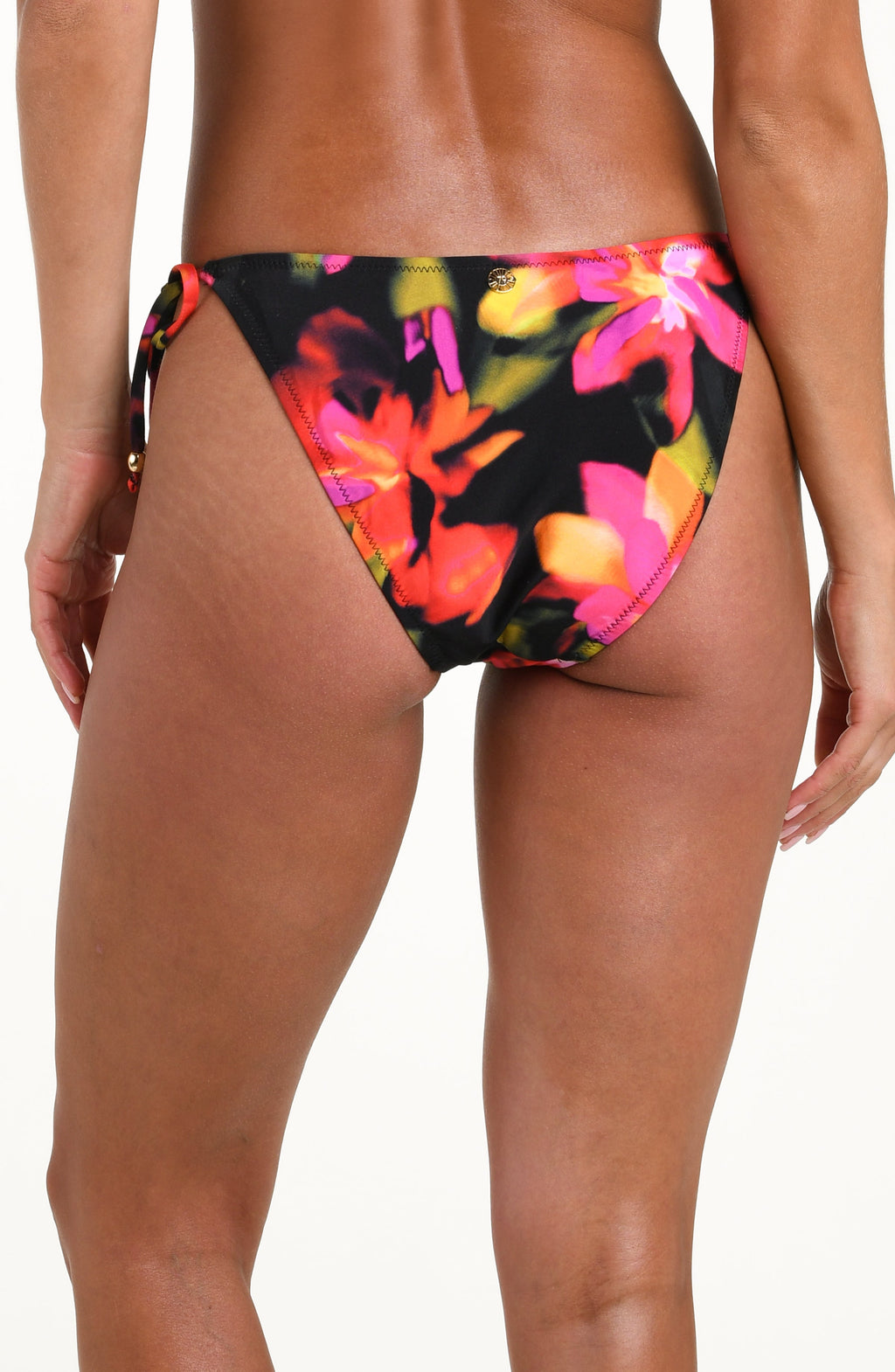 Back image of model wearing bikini bottoms with side tie detail, gold charm at center, and contemporary coverage in a multicolored floral print.