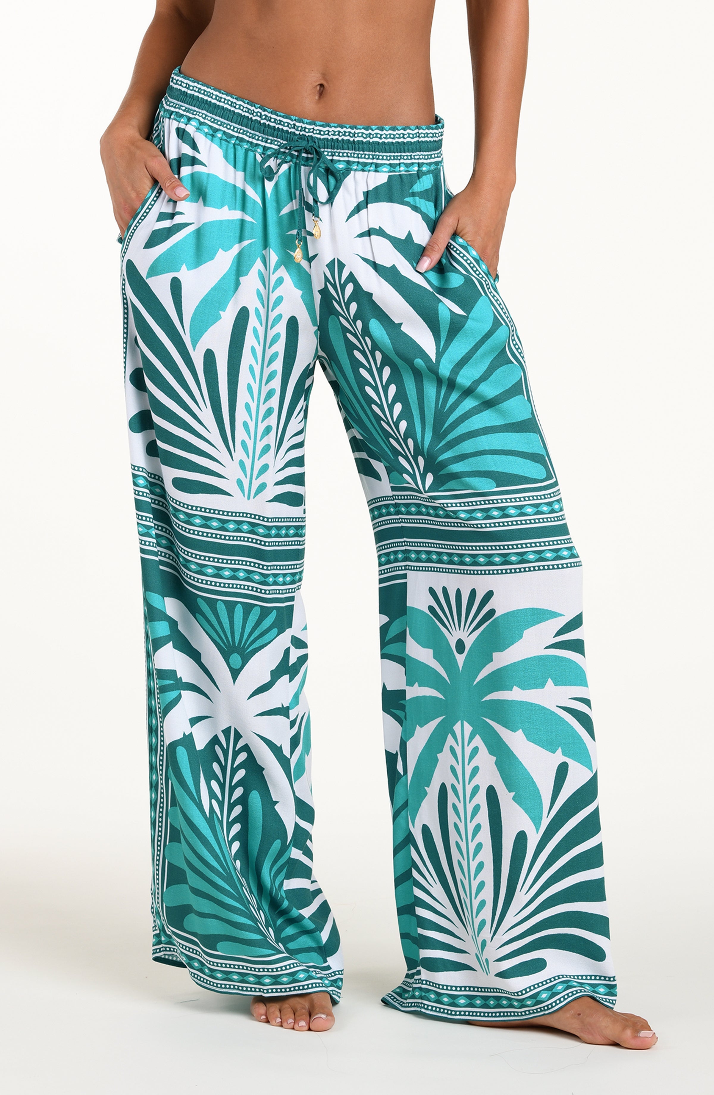 Teal and white patterned pants worn by a person on a white background