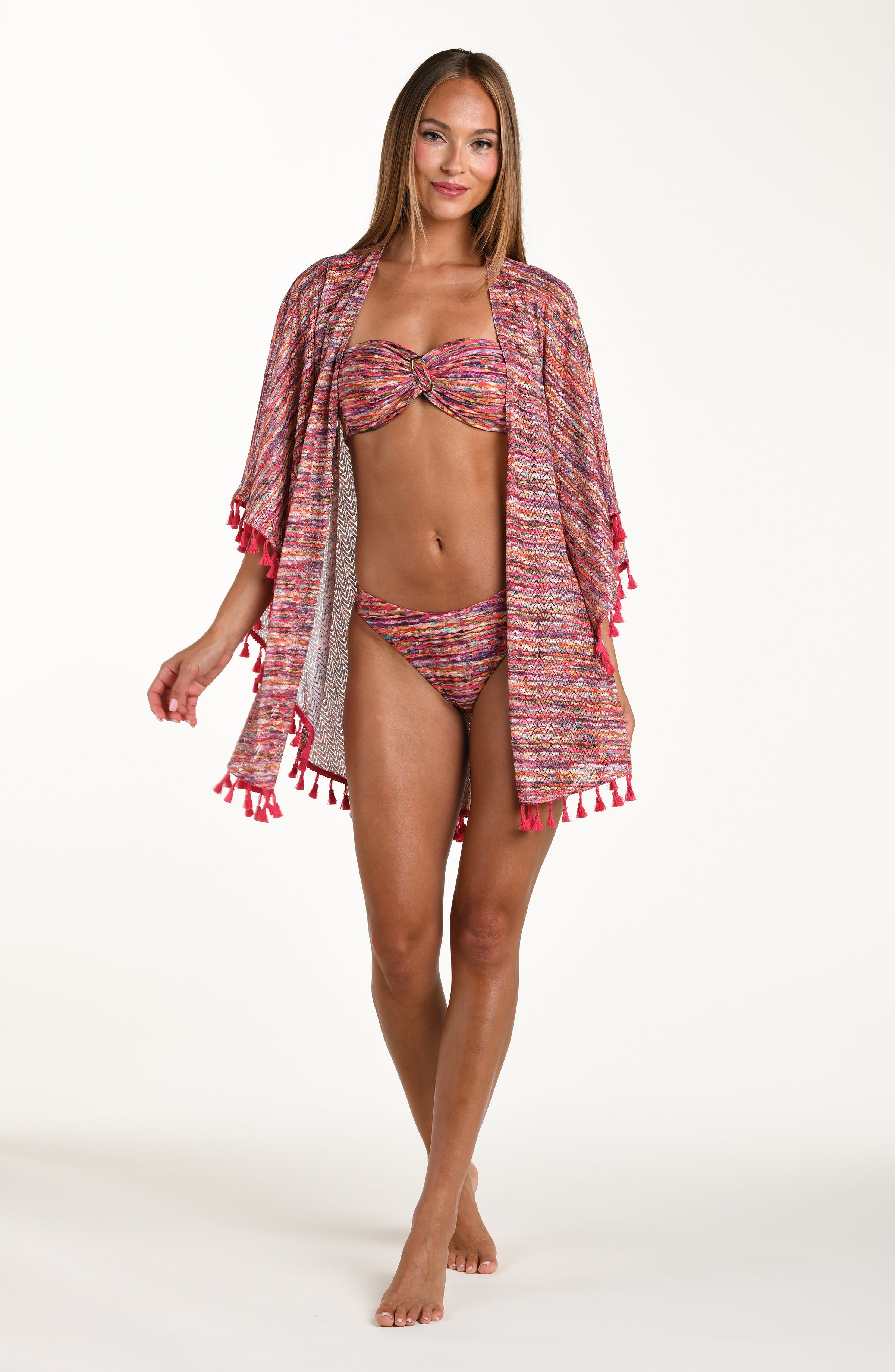 Full body front image of model wearing an open front kimono cover up with three quarter sleeves and tassel trim featuring a multicolored ripple print.