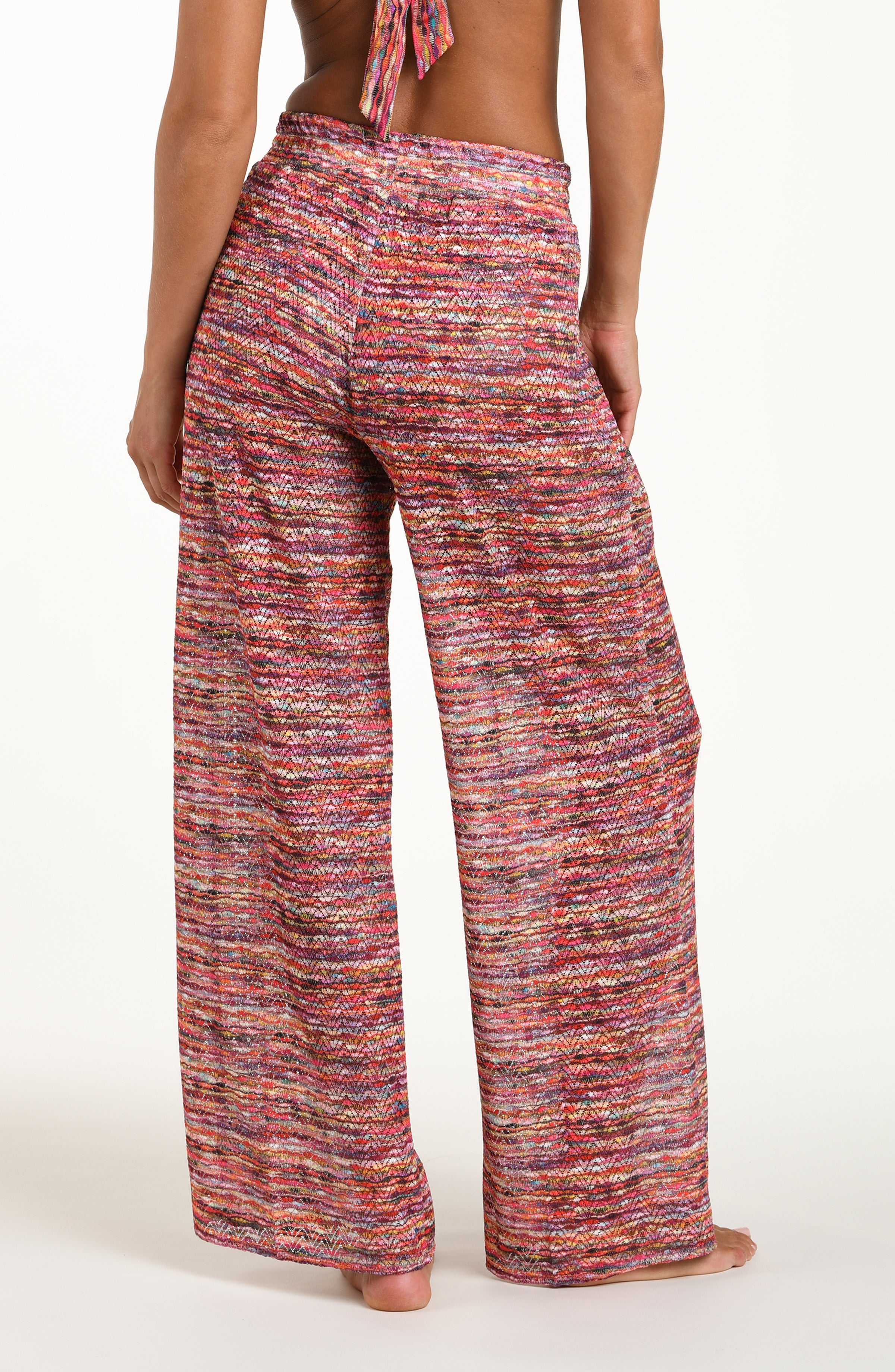 Back image of model wearing long beach pants in a multicolored ripple pattern featuring an elastic waist. 