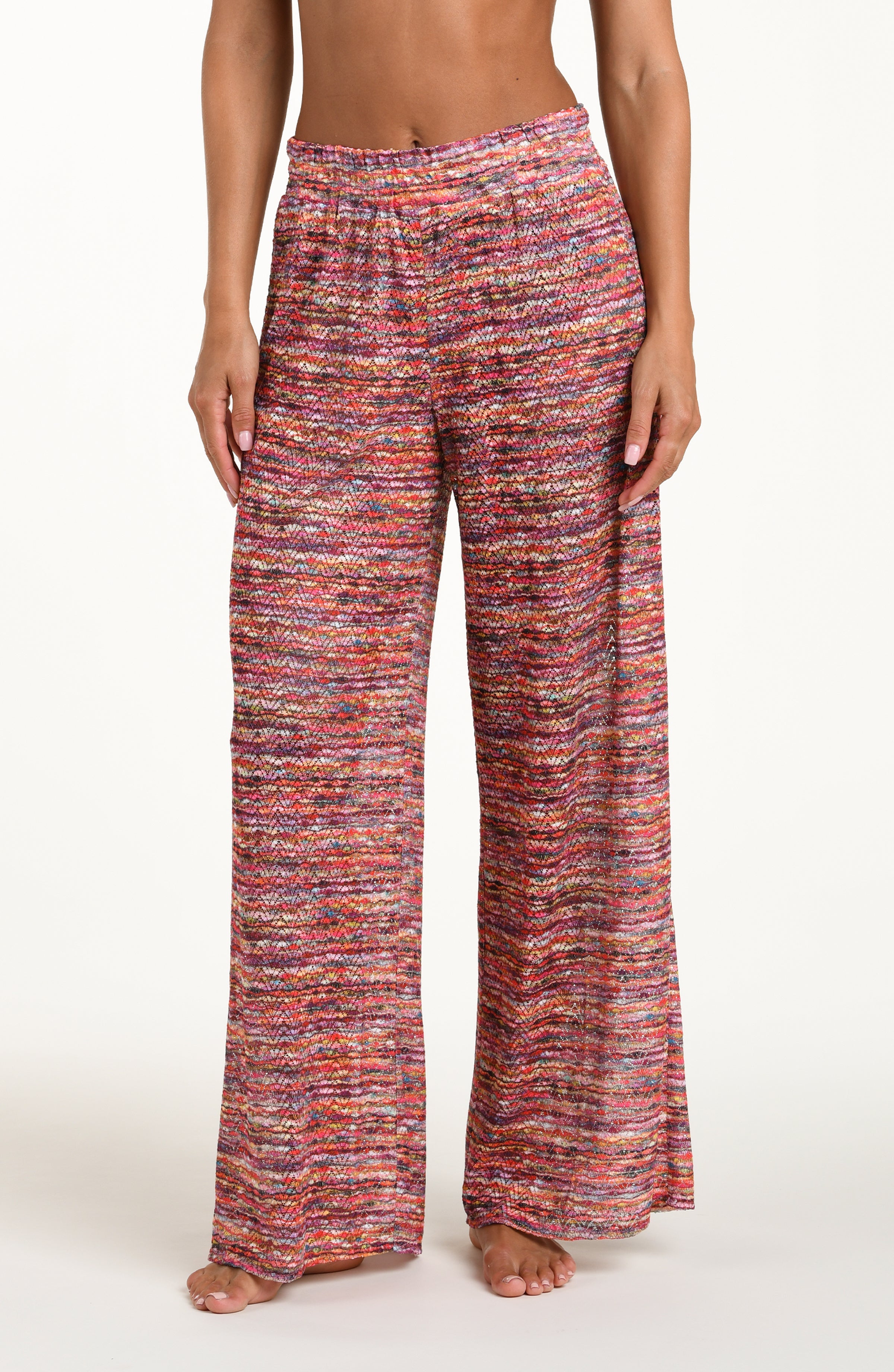 Front image of model wearing long beach pants in a multicolored ripple pattern featuring an elastic waist. 
