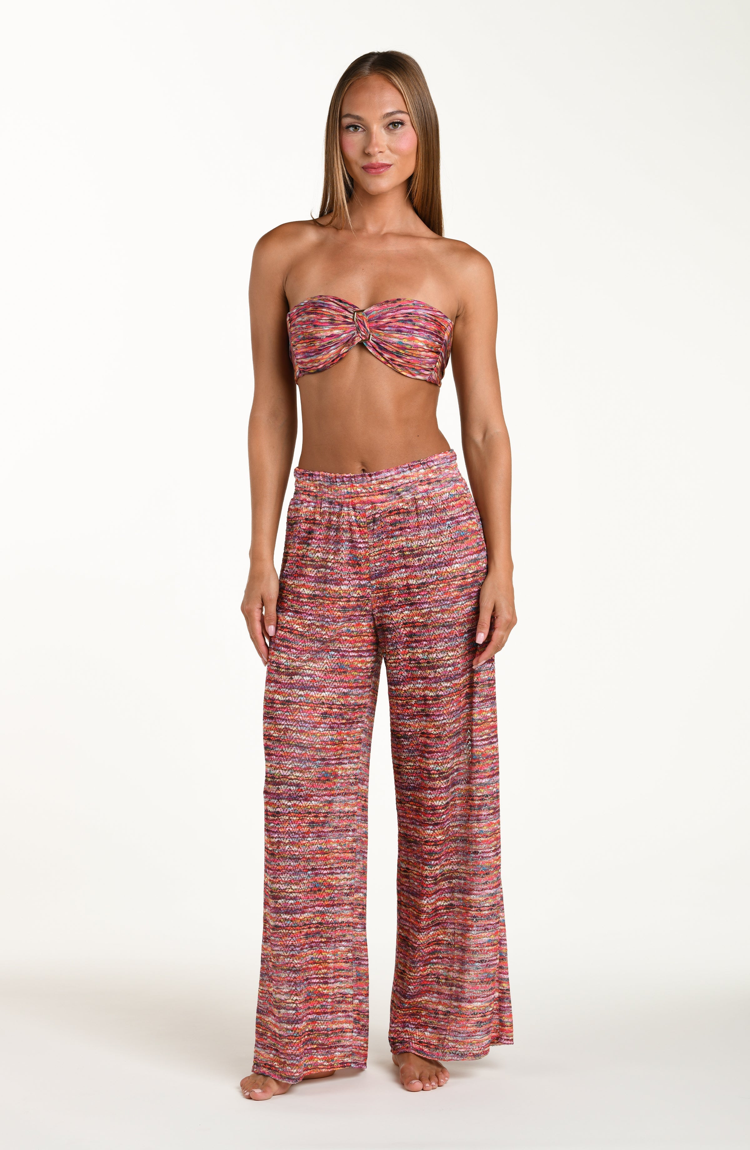 Full body front image of model wearing long beach pants in a multicolored ripple pattern featuring an elastic waist. This is paired with a matching bikini top.