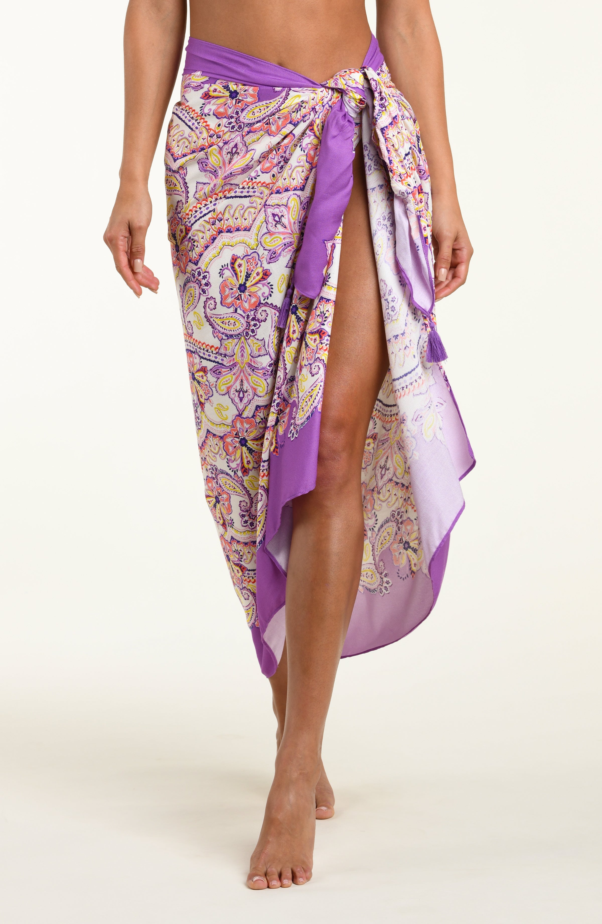 Person wearing a colorful patterned sarong with a purple top on a white background