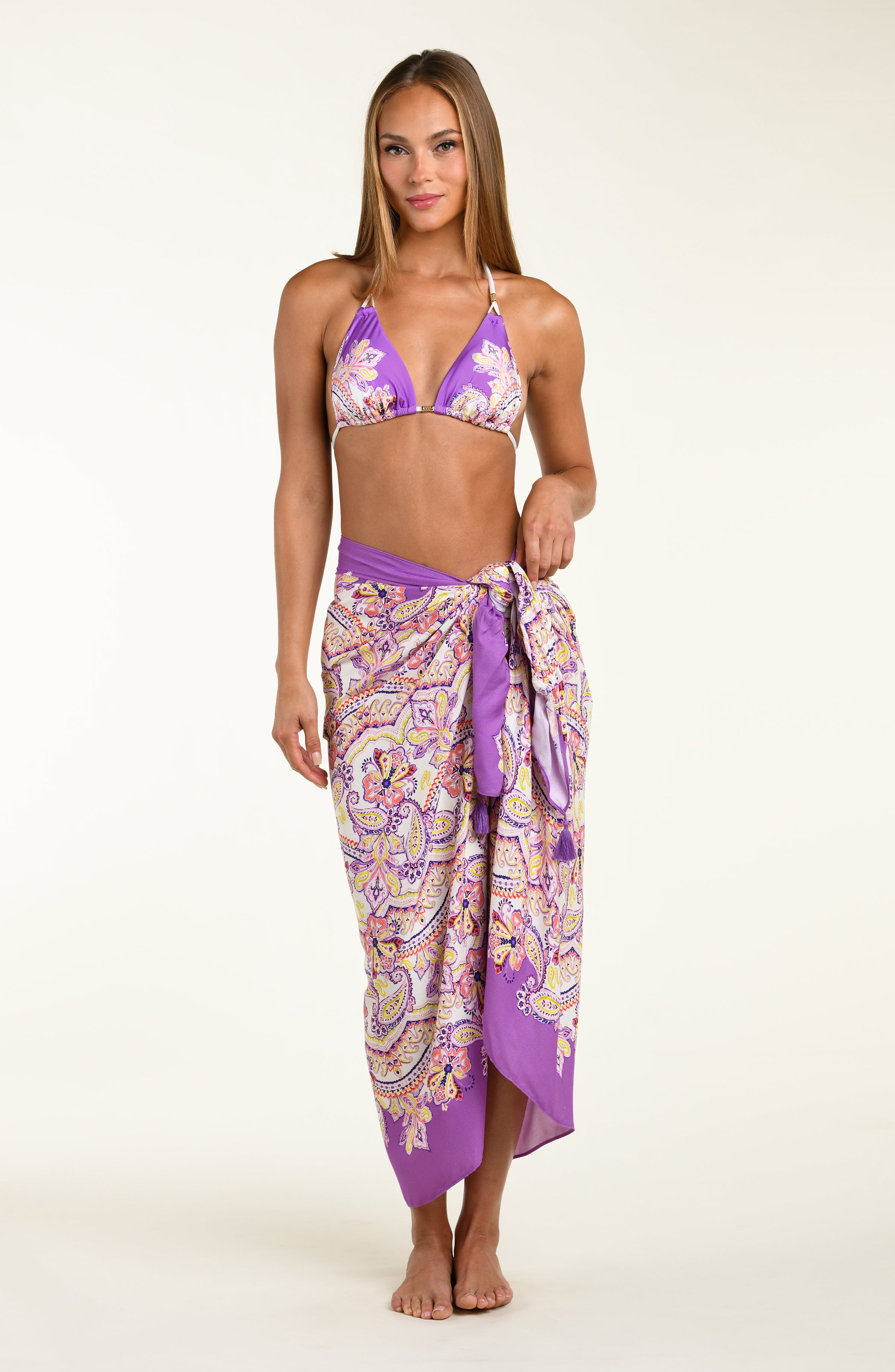 Person wearing a colorful patterned sarong with a purple top on a white background