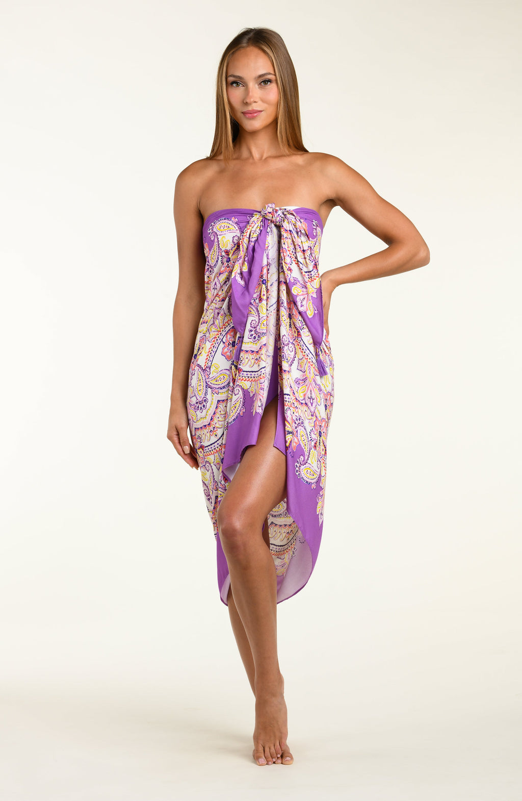 Person wearing a colorful patterned sarong with a purple top on a white background