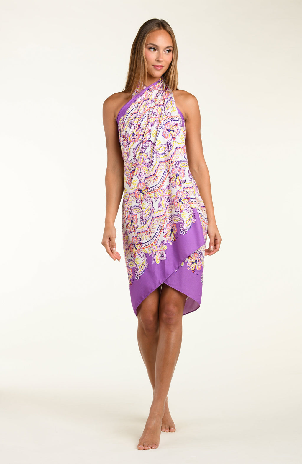 Person wearing a colorful patterned sarong with a purple top on a white background