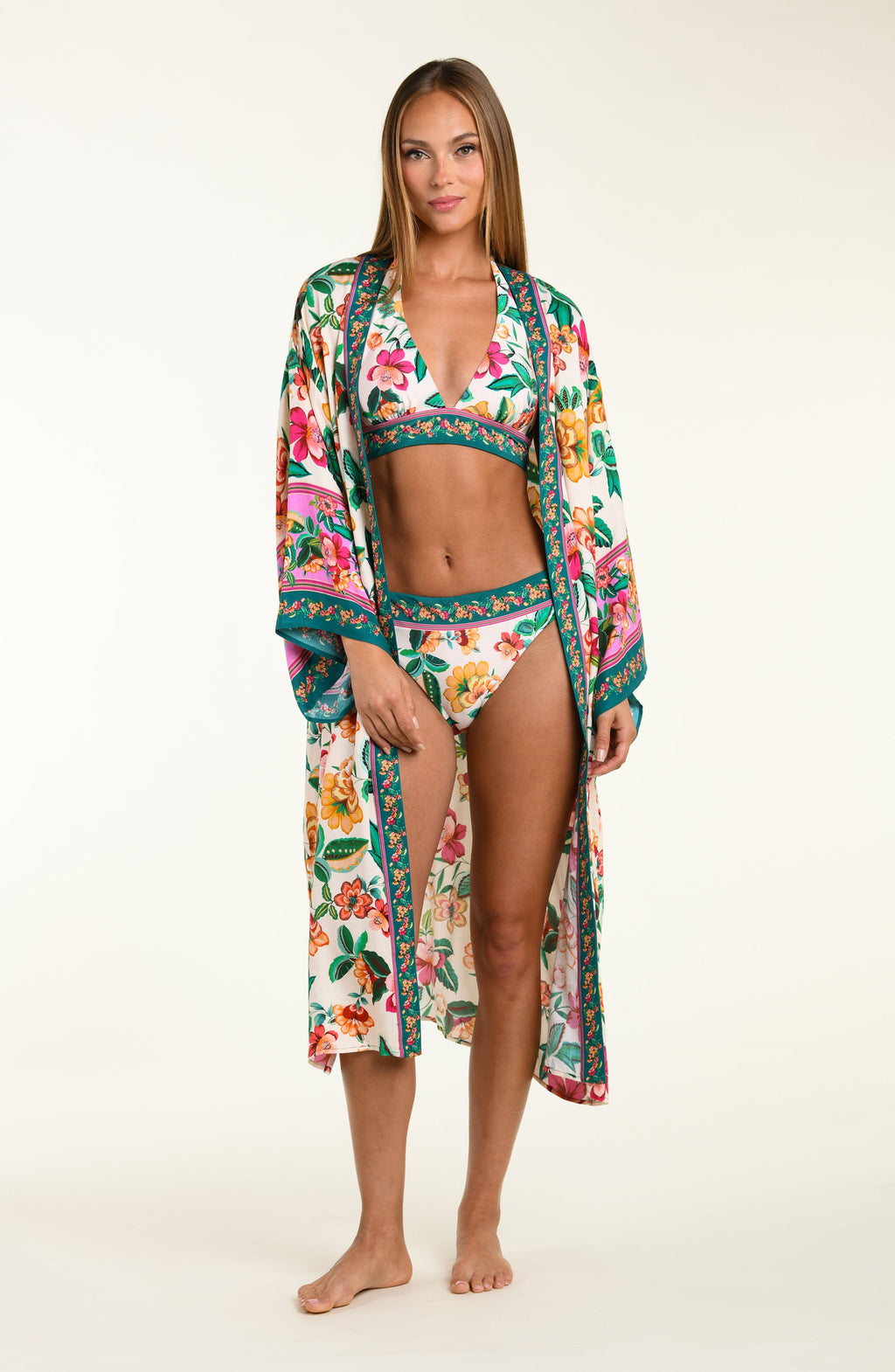 Woman wearing a colorful floral swimsuit with matching kimono cover-up on a white background