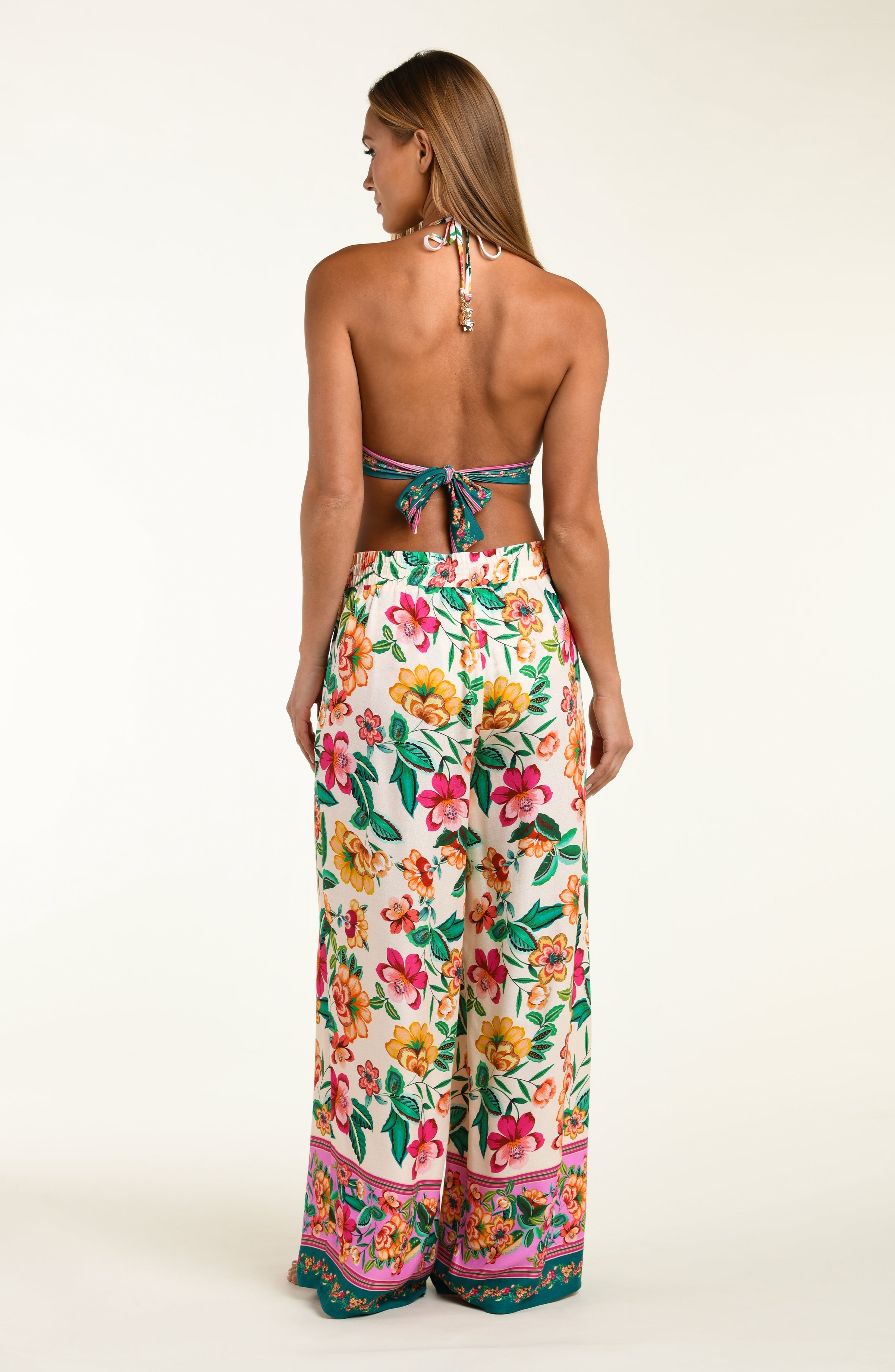 Woman wearing a floral bikini top and matching beach pants on a white background