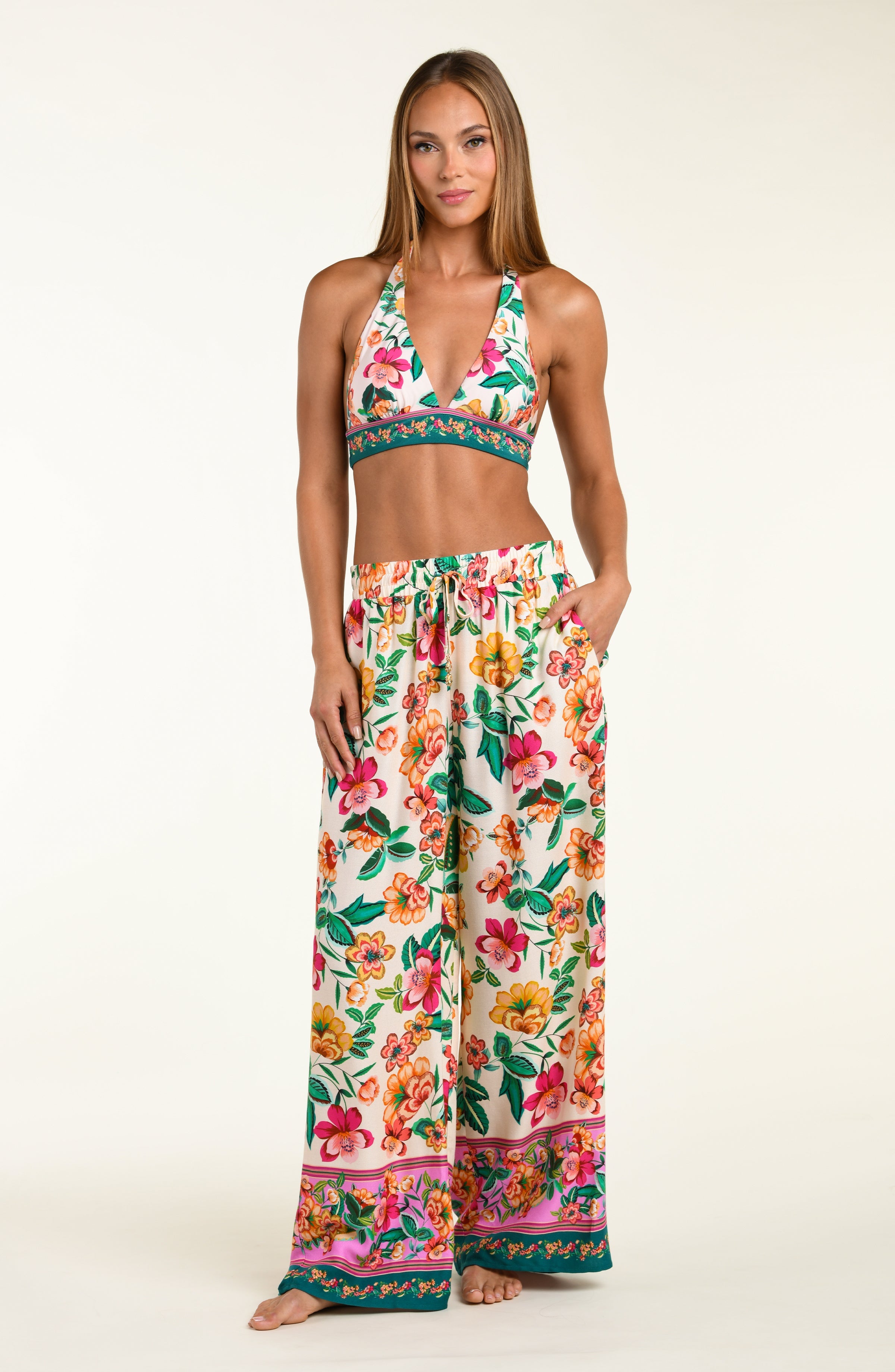 Woman wearing a floral bikini top and matching beach pants on a white background