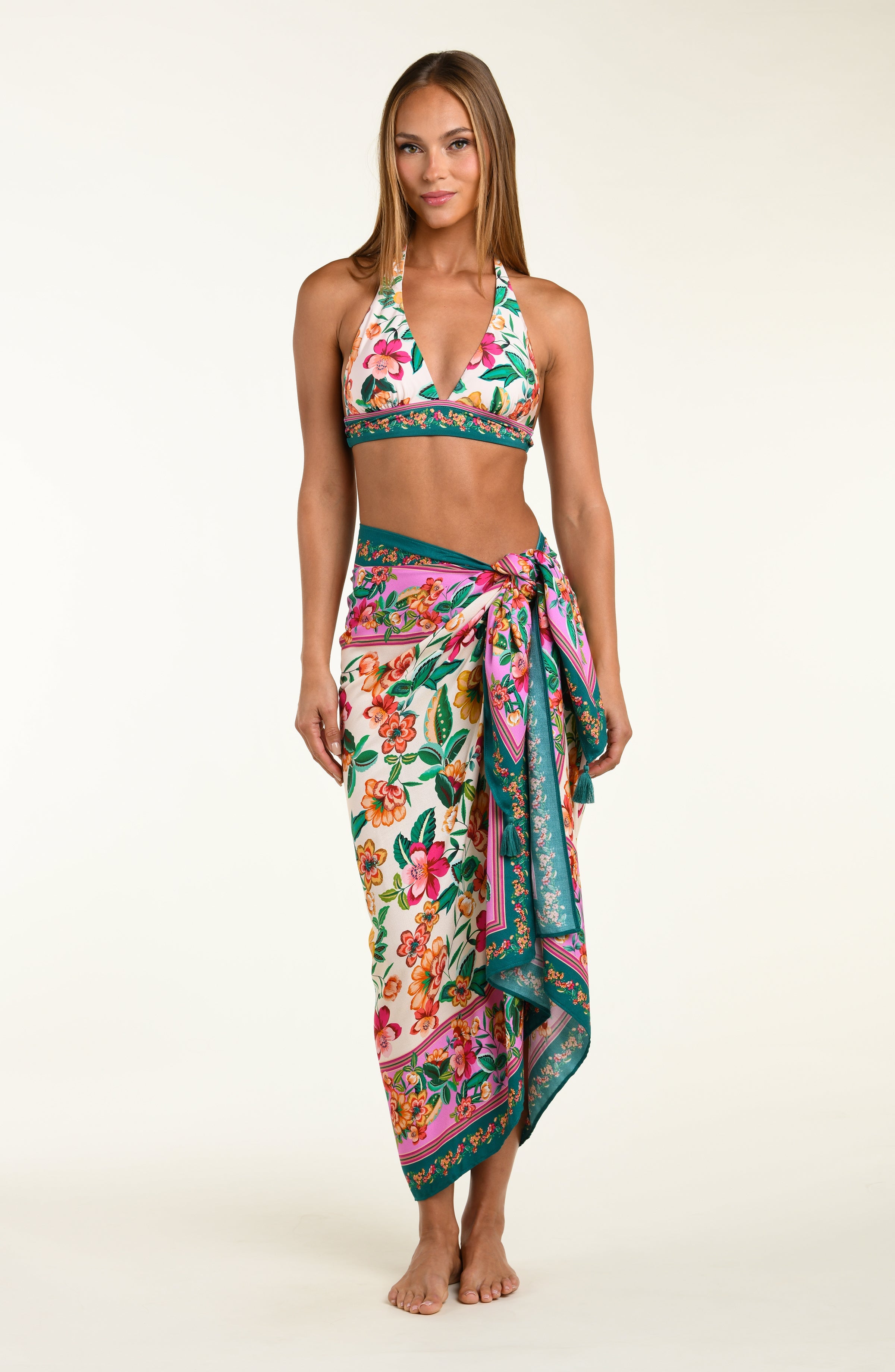 Woman wearing a floral bikini top and matching sarong on a white background