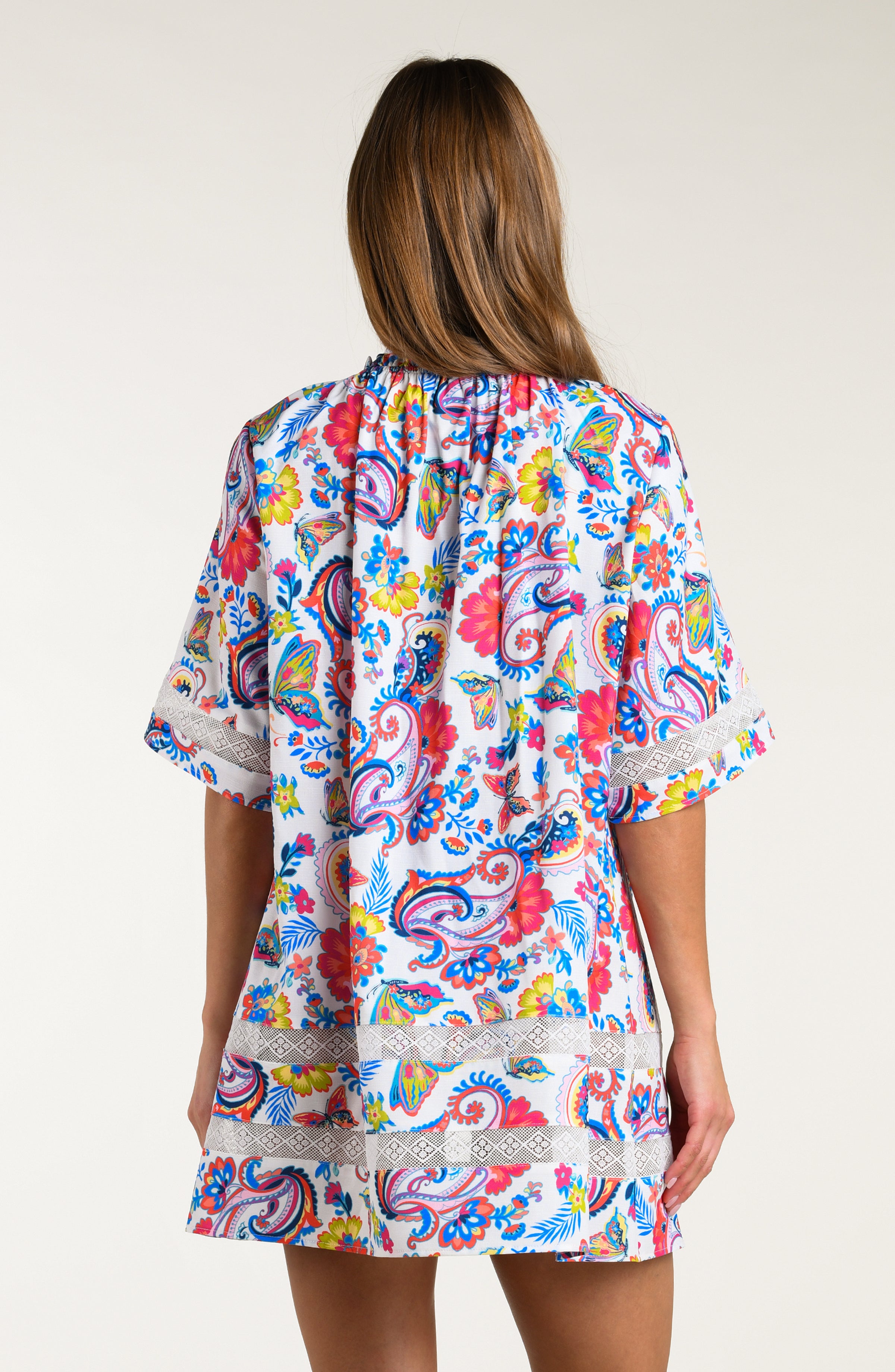 Woman wearing a multicolored tunic cover up against a white background.