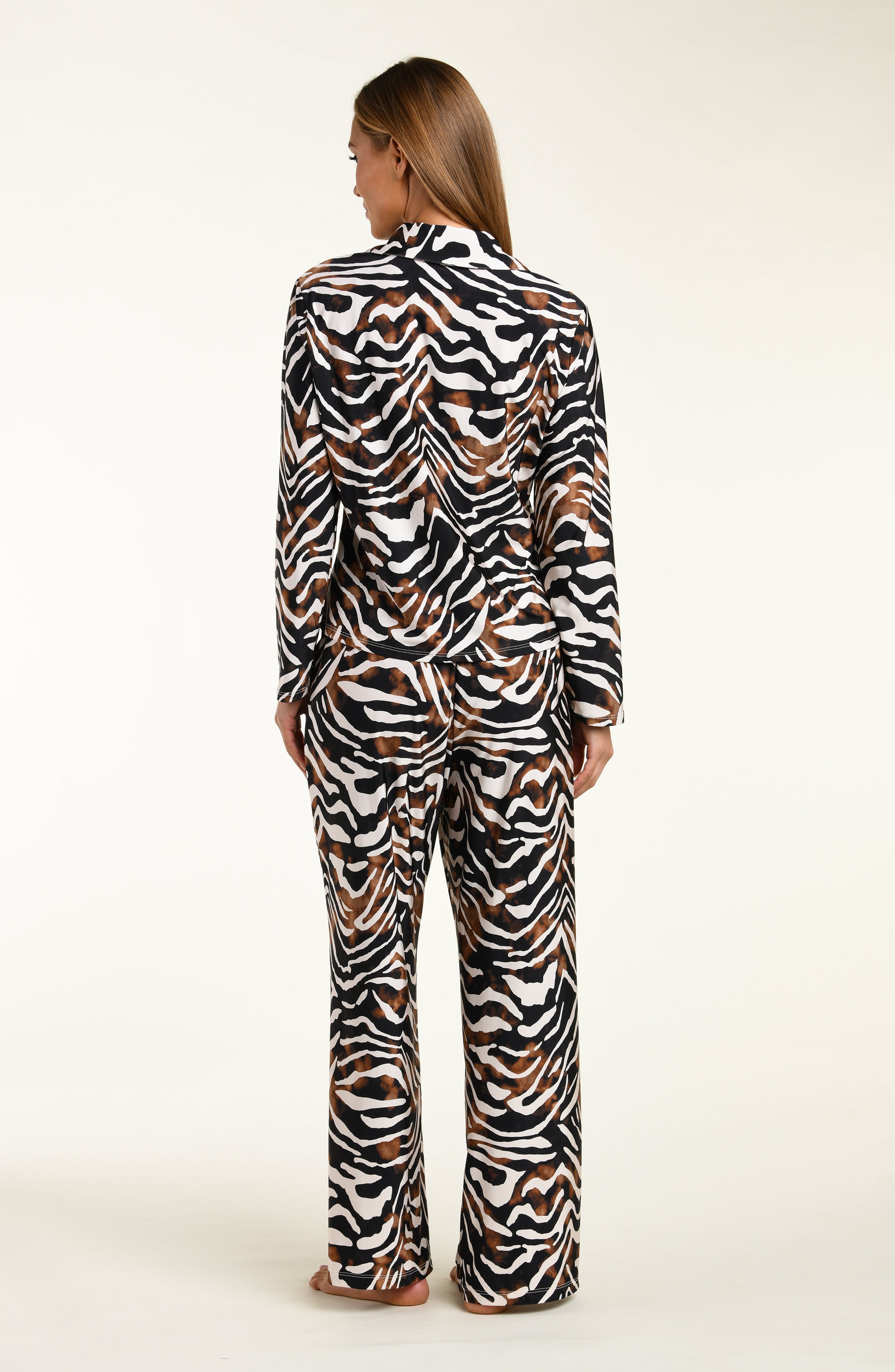 Woman wearing an animal printed shirt and pant matching pajama set on a white background