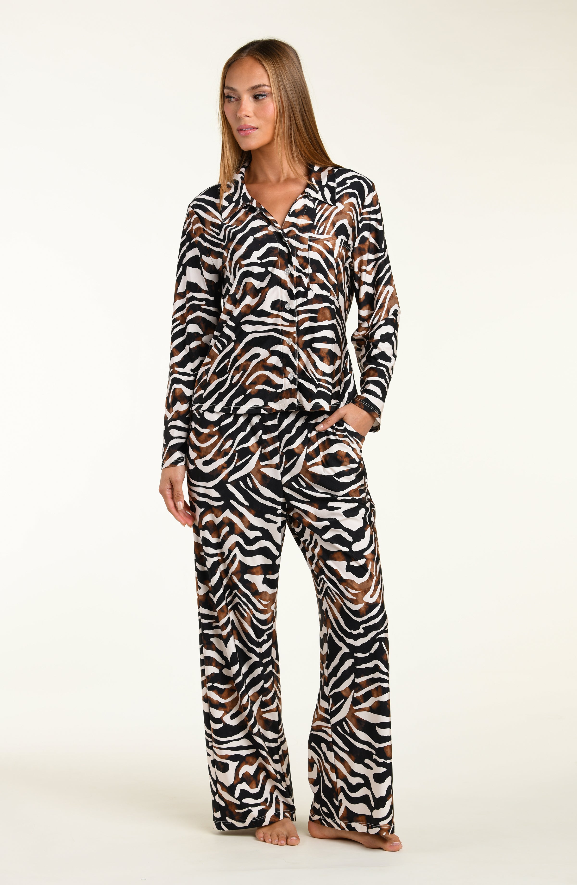 Woman wearing an animal printed shirt and pant matching pajama set on a white background