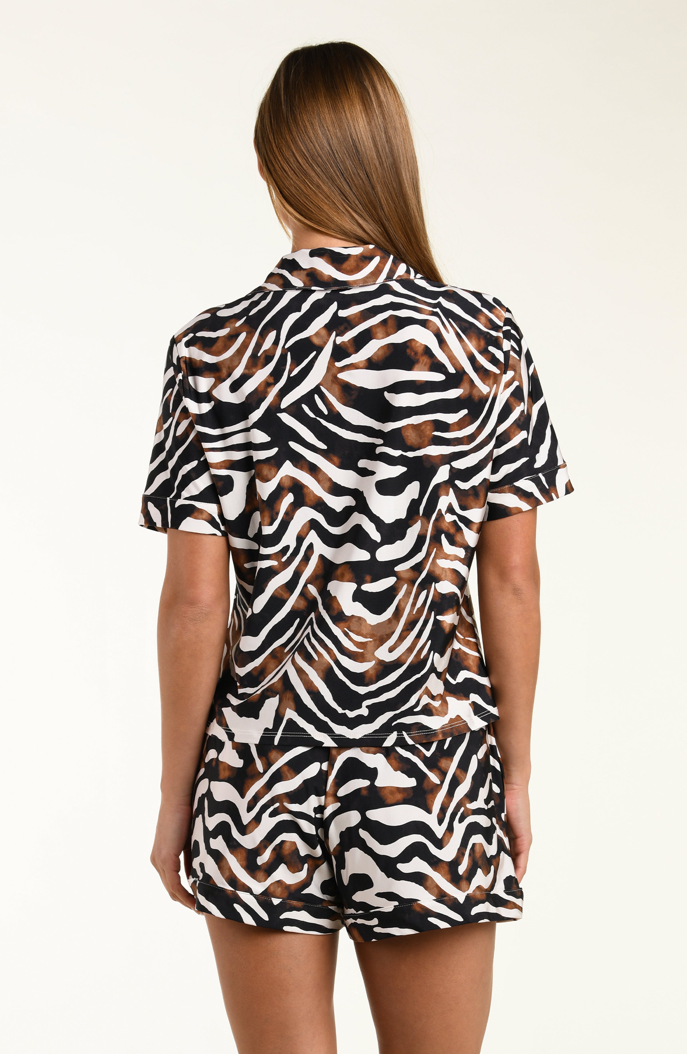Woman wearing an animal printed shirt and short matching pajama set on a white background