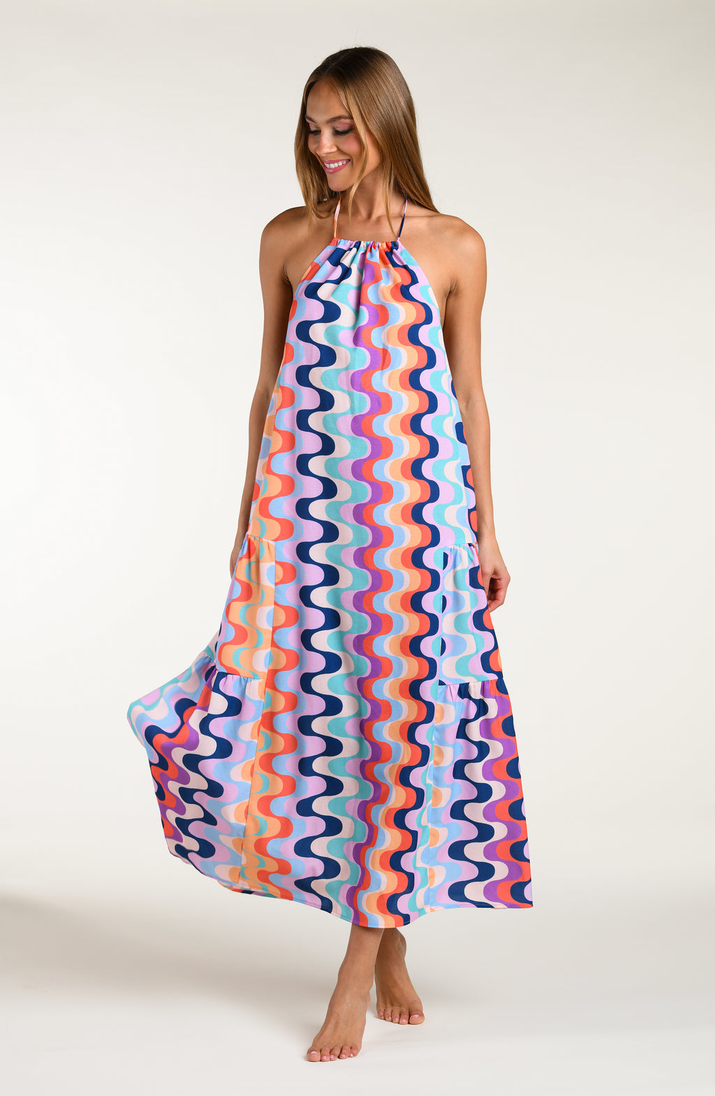 Woman wearing a colorful patterned maxi dress on a white background
