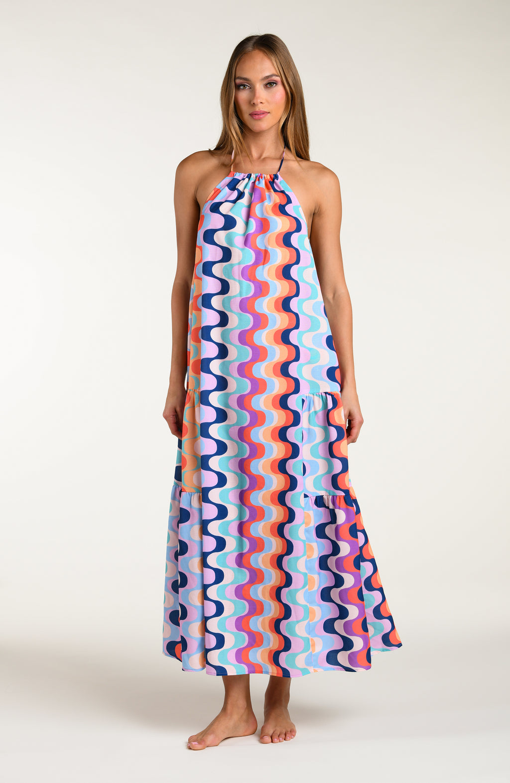 Woman wearing a colorful patterned maxi dress on a white background