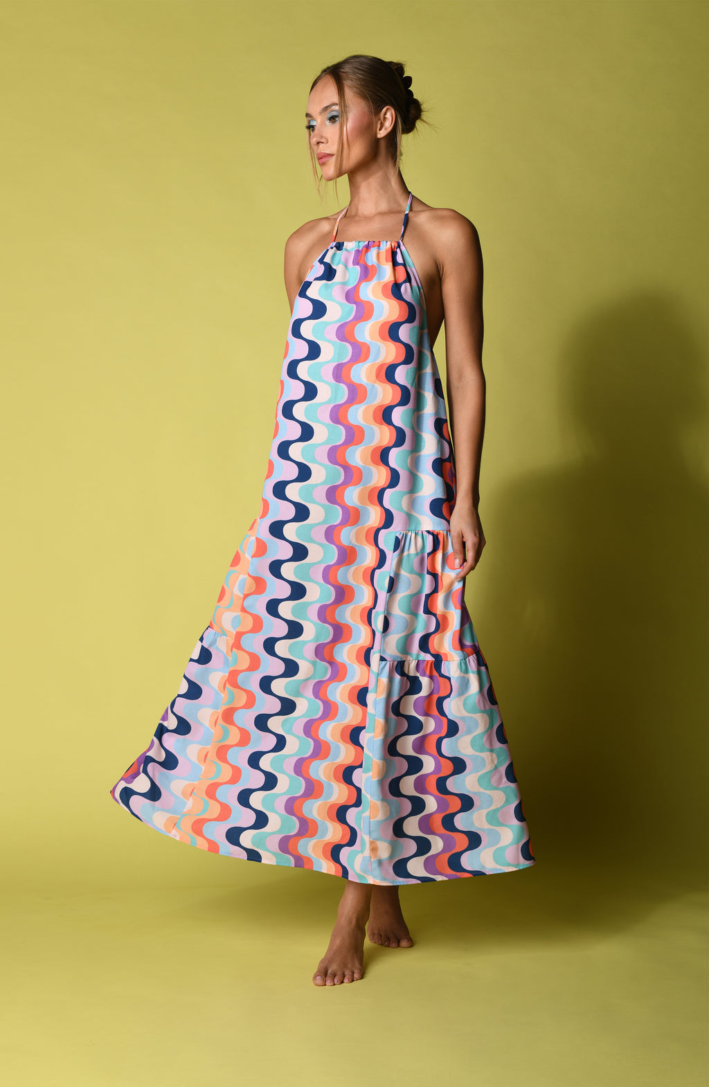 Woman wearing a multicolored maxi dress against a yellow background