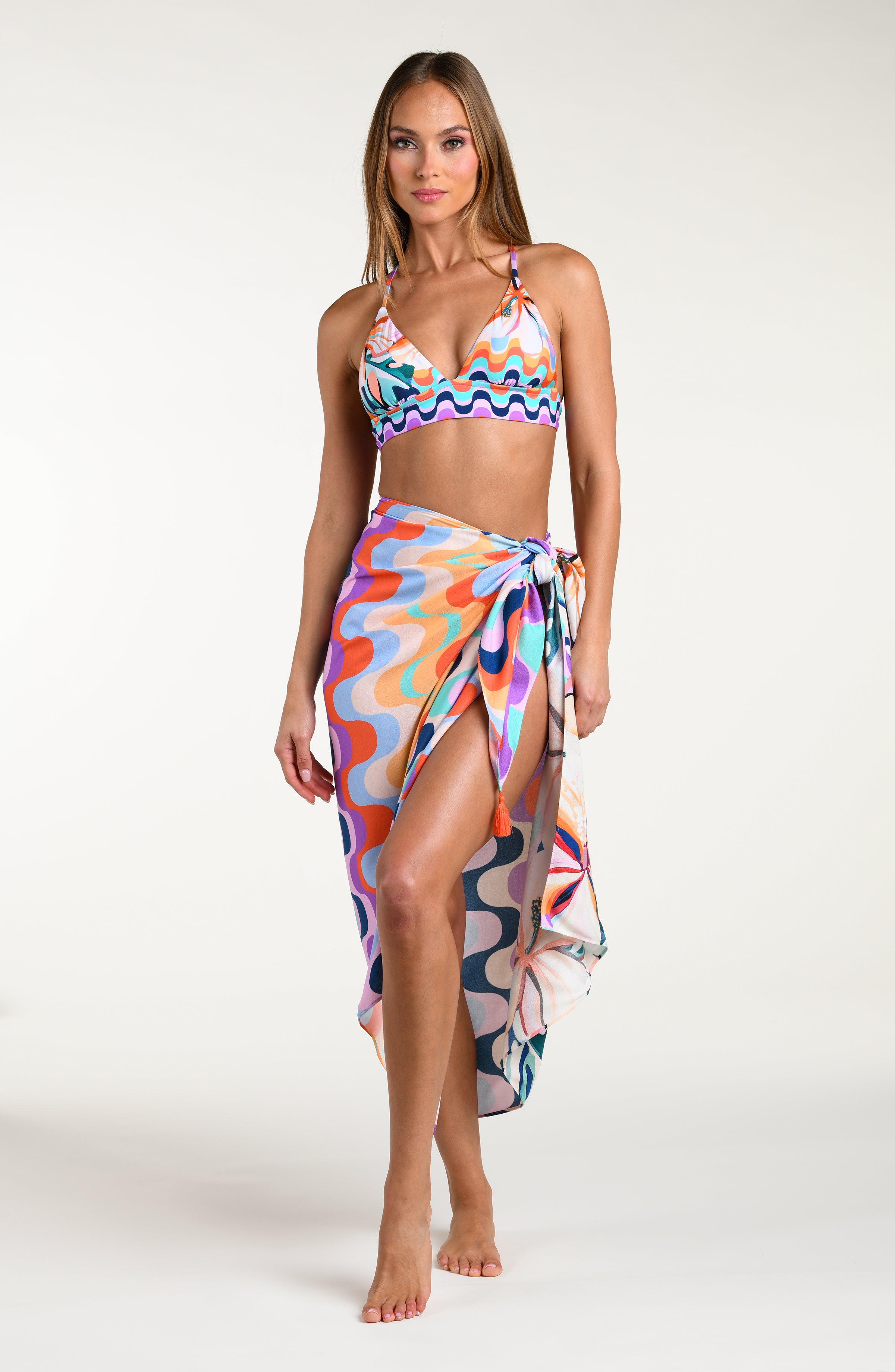 Woman wearing a multicolored patterned bikini top and matching sarong on a white background