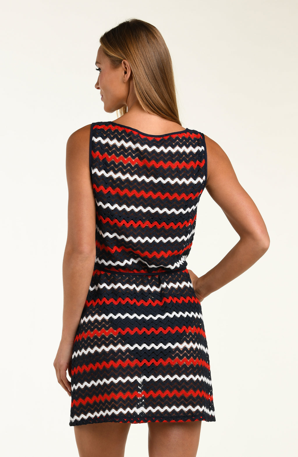 Woman wearing a sleeveless dress with red, white, and black zigzag pattern on a beige background