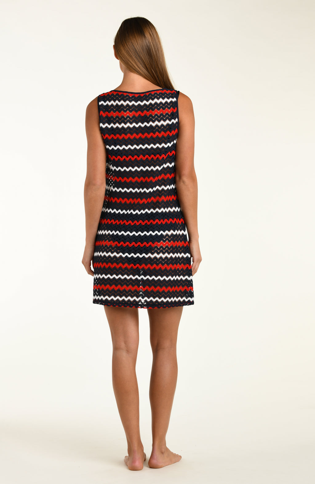 Woman wearing a sleeveless dress with red, white, and black zigzag pattern on a beige background
