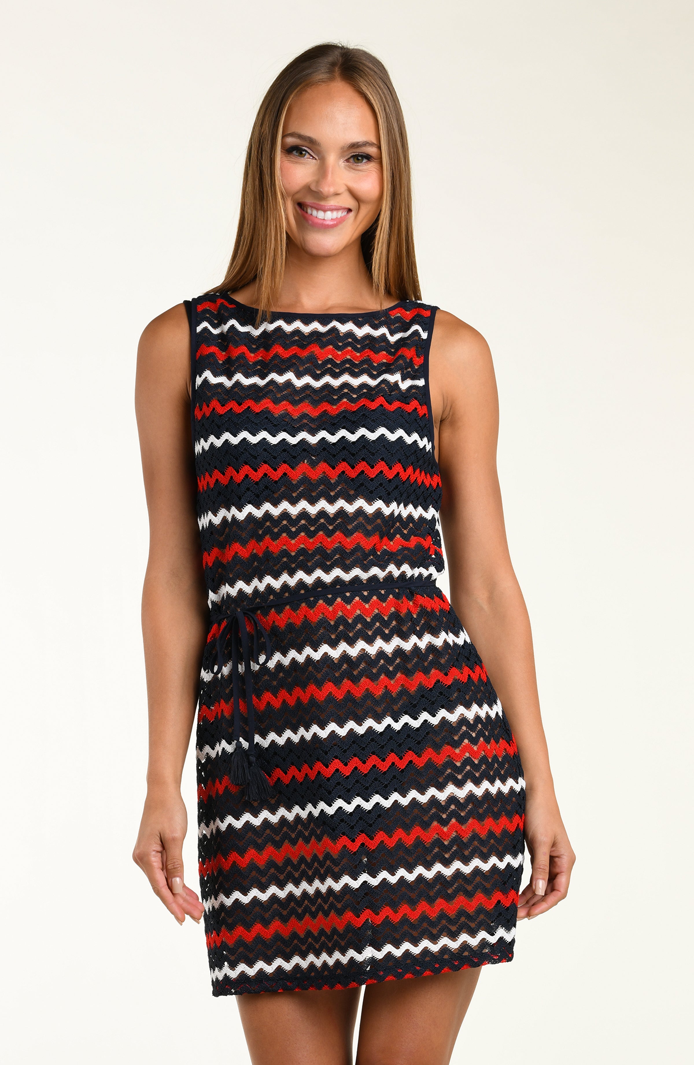 Woman wearing a sleeveless dress with red, white, and black zigzag pattern on a beige background