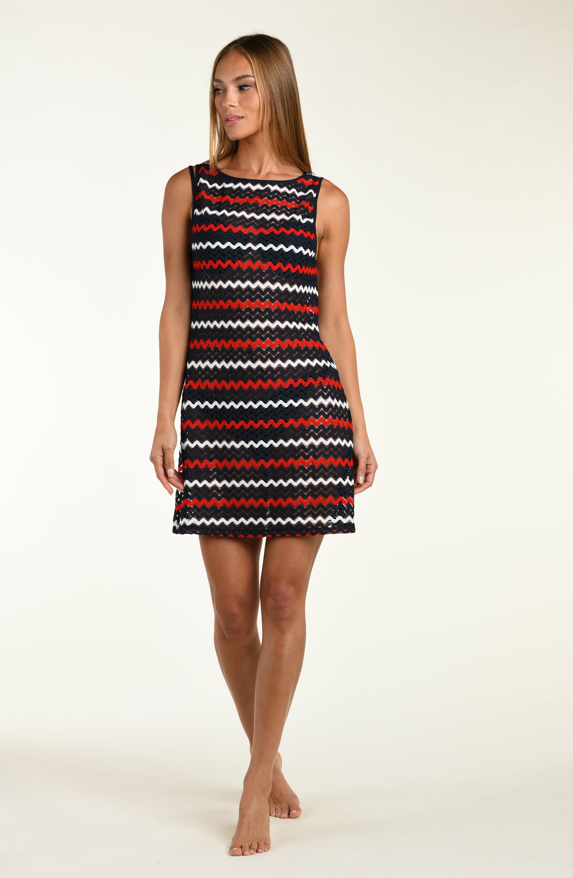 Woman wearing a sleeveless dress with red, white, and black zigzag pattern on a beige background