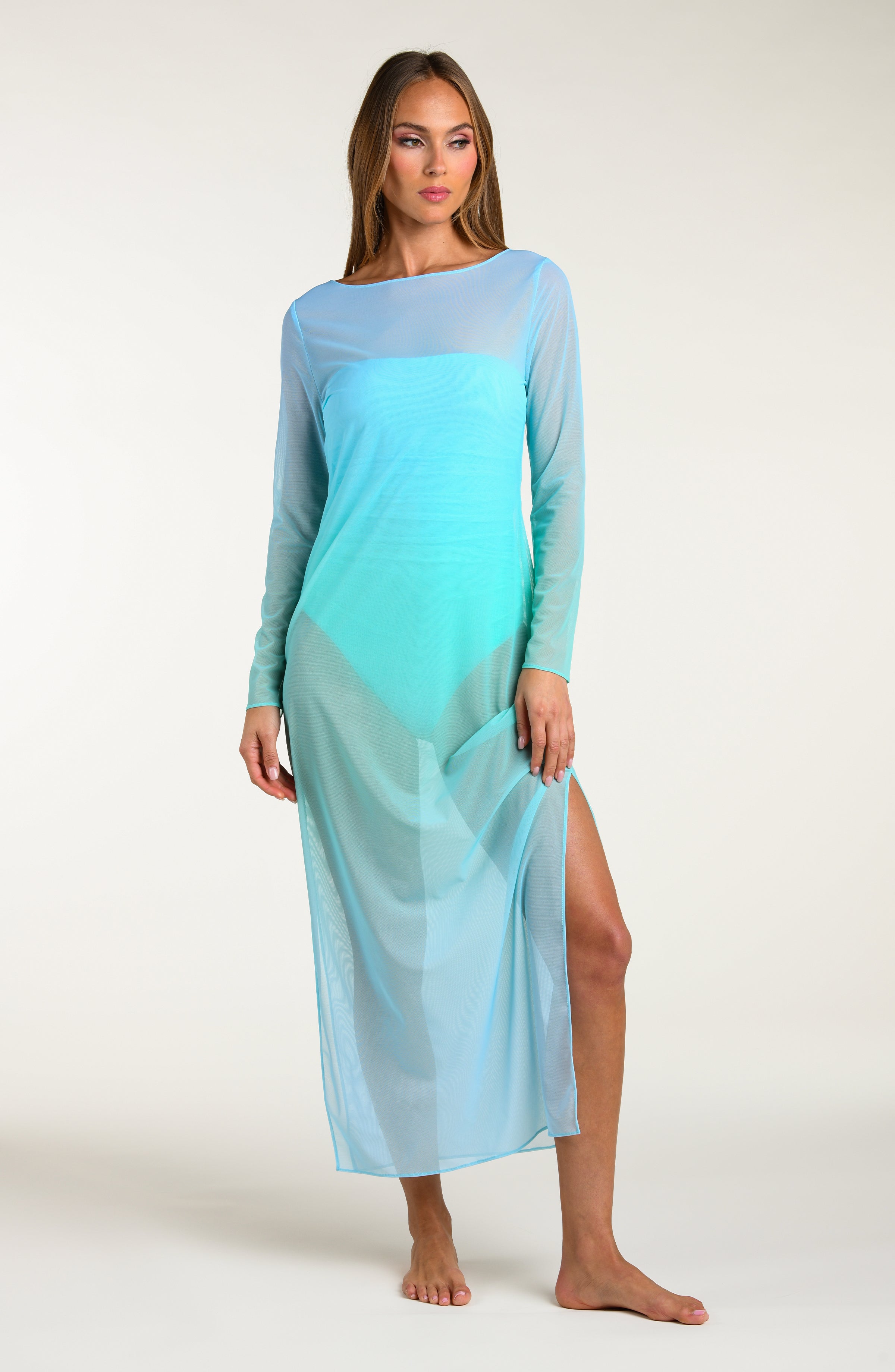 Woman wearing a long, turquoise maxi dress with a gradient effect against a white background