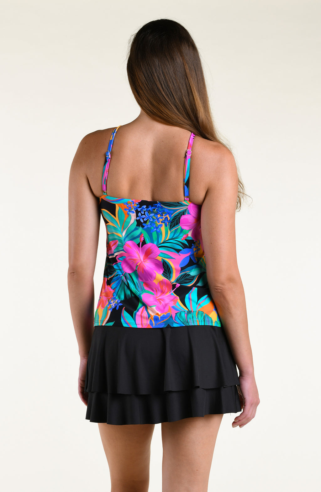 Woman wearing a bright multicolored high neck tankini top and solid black swim skirt against a white background. 