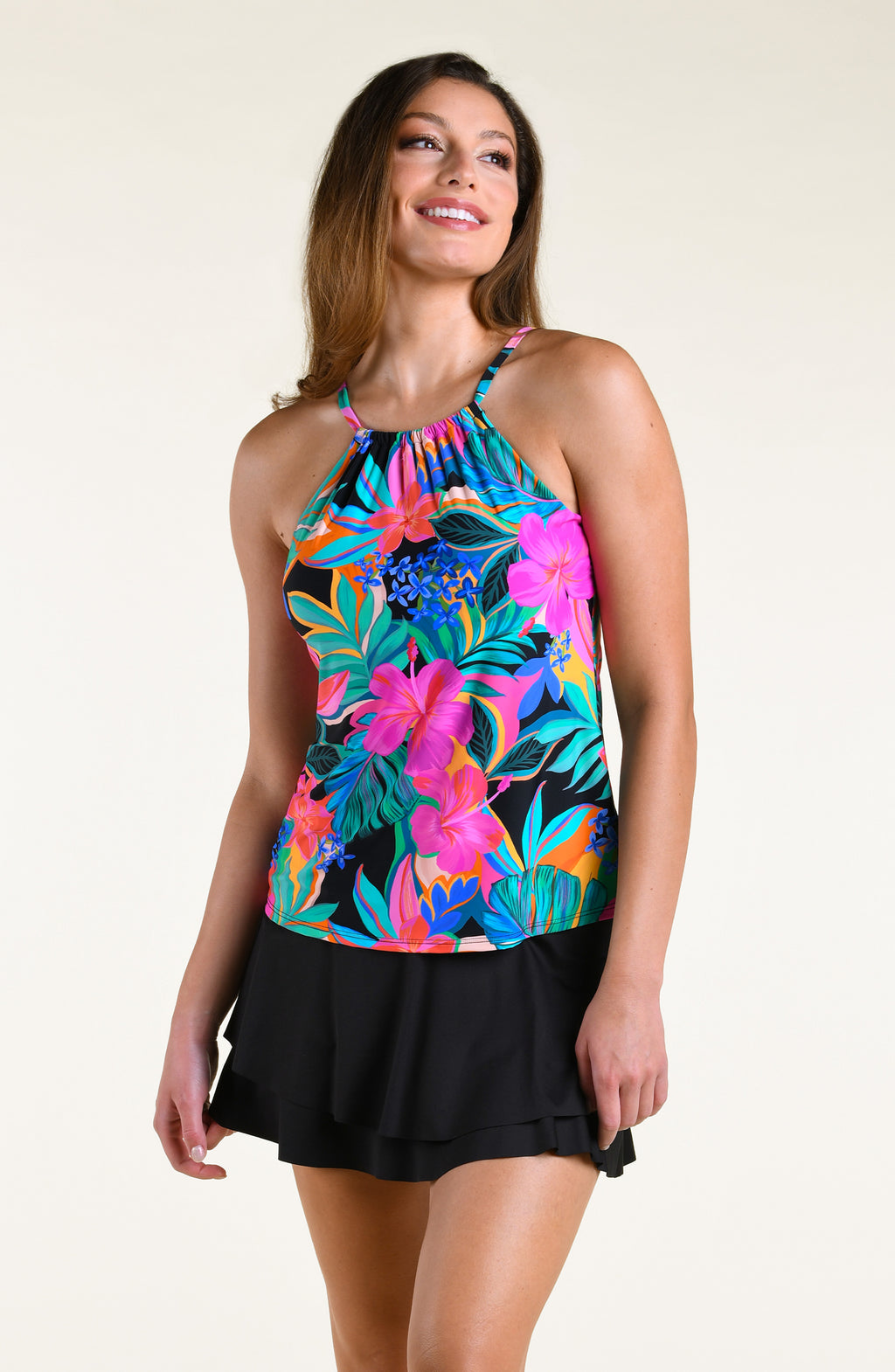 Woman wearing a bright multicolored high neck tankini top and solid black swim skirt against a white background. 