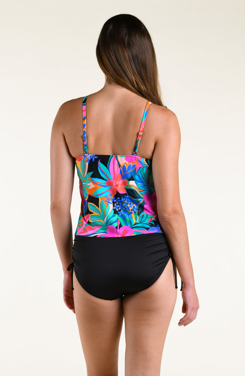 Woman wearing a bright multicolored tankini top and solid bikini bottom against a white background. 