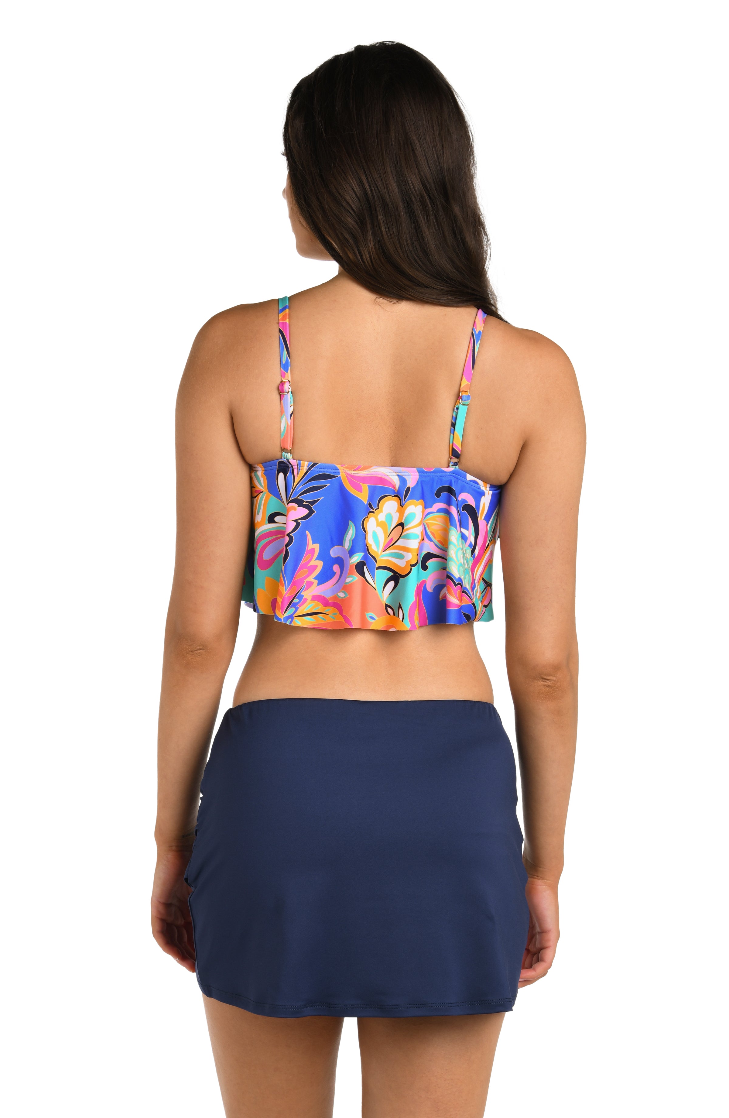 Woman wearing a colorful floral tankini top and navy swim skirt on a white background