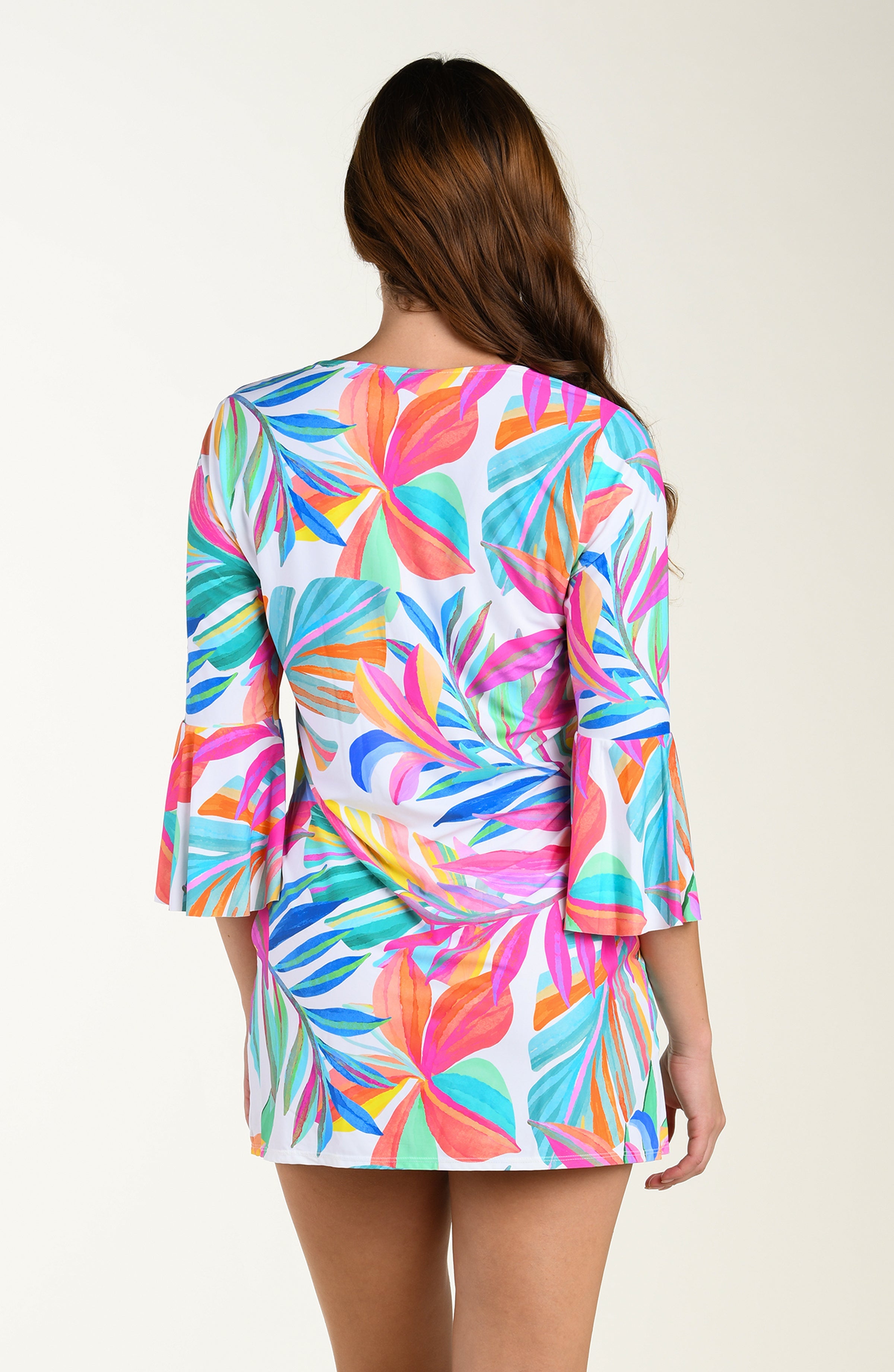 Back image of model wearing a multicolored (mostly pink) tropical printed cover-up dress featuring a relaxed, flowy fit with three-quarter sleeves, a tie-front neckline, and pockets.