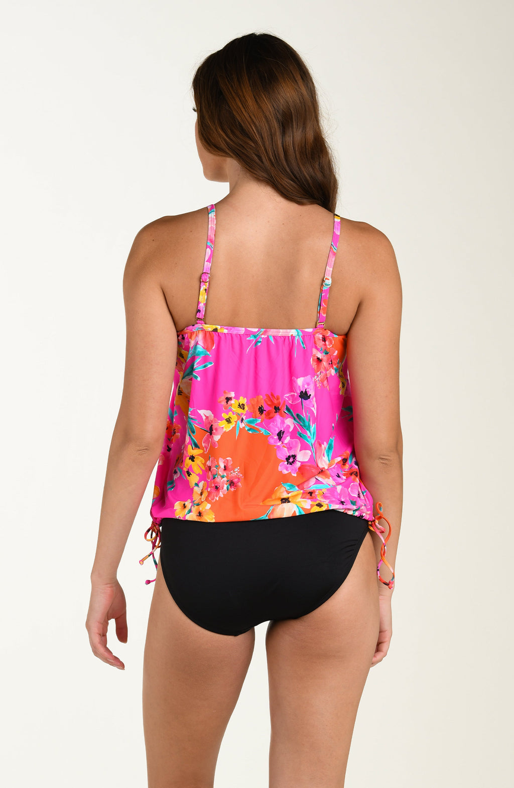 Back image of model wearing a multicolored pink floral printed tankini top featuring a relaxed, flowy fit with adjustable straps, straight back, and a drawstring hem for customizable style. This is paired with solid black colored bikini bottoms.