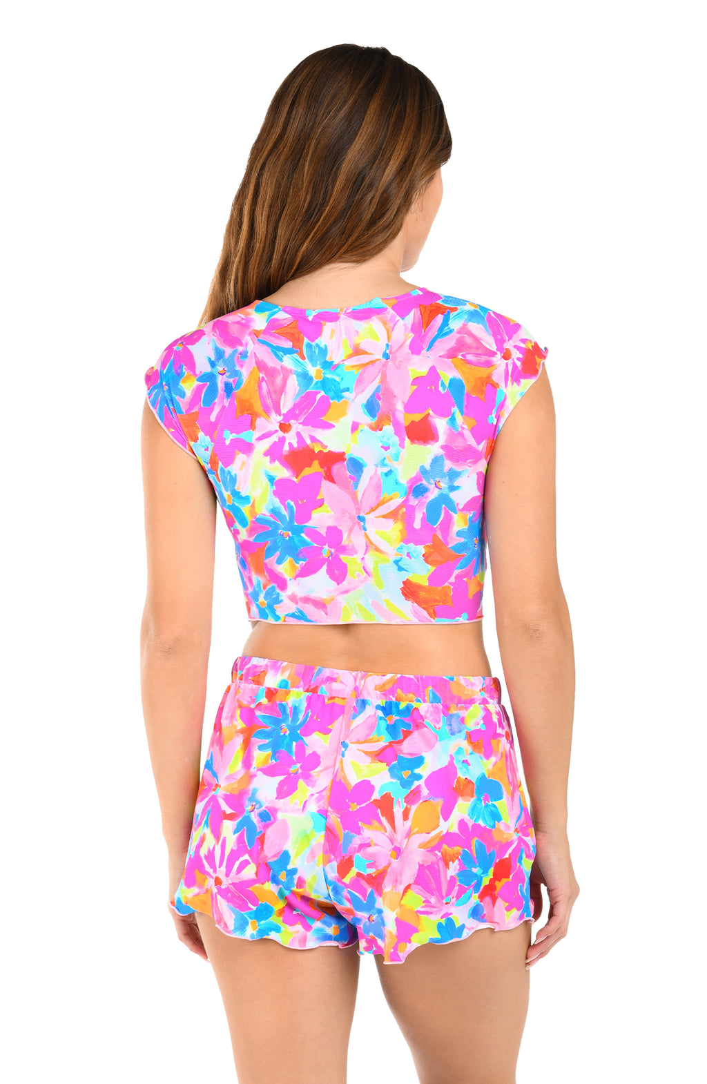 Woman wearing a colorful floral cropped rash guard and matching shorts worn by a person on a white background