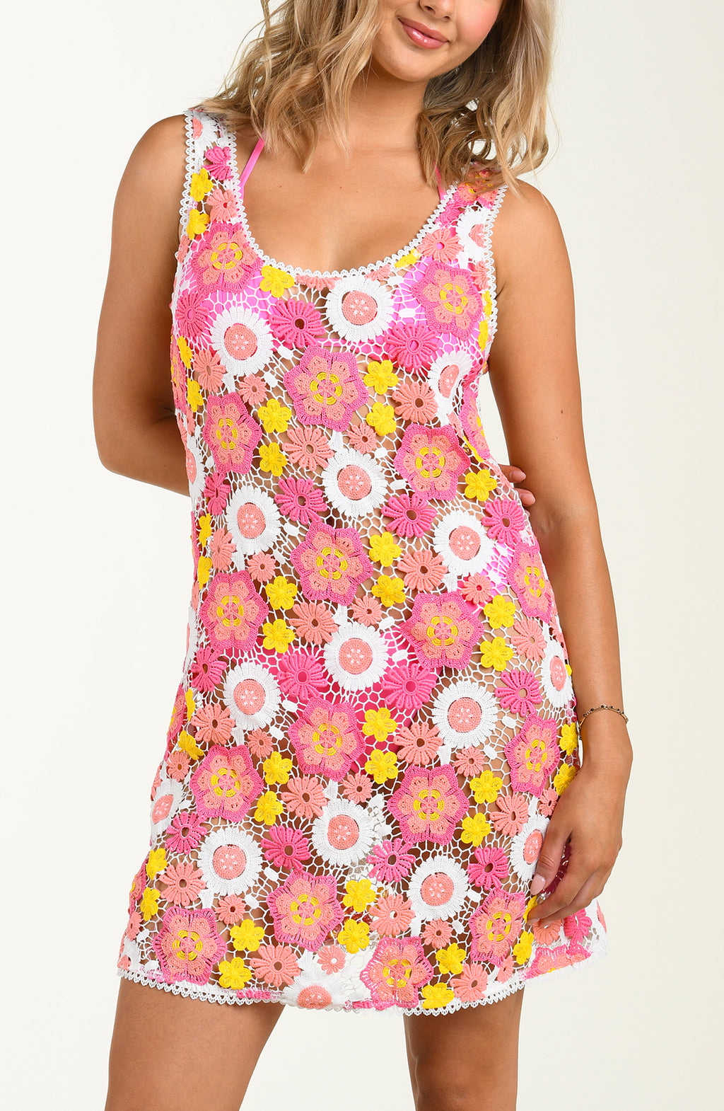 Woman wearing a colorful crochet dress with floral patterns on a plain background