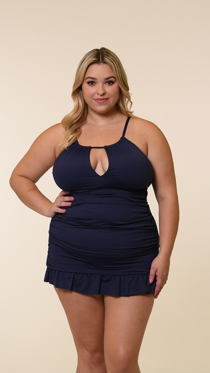 Video of a woman wearing an indigo blue tankini top and matching swim skirt with a white background