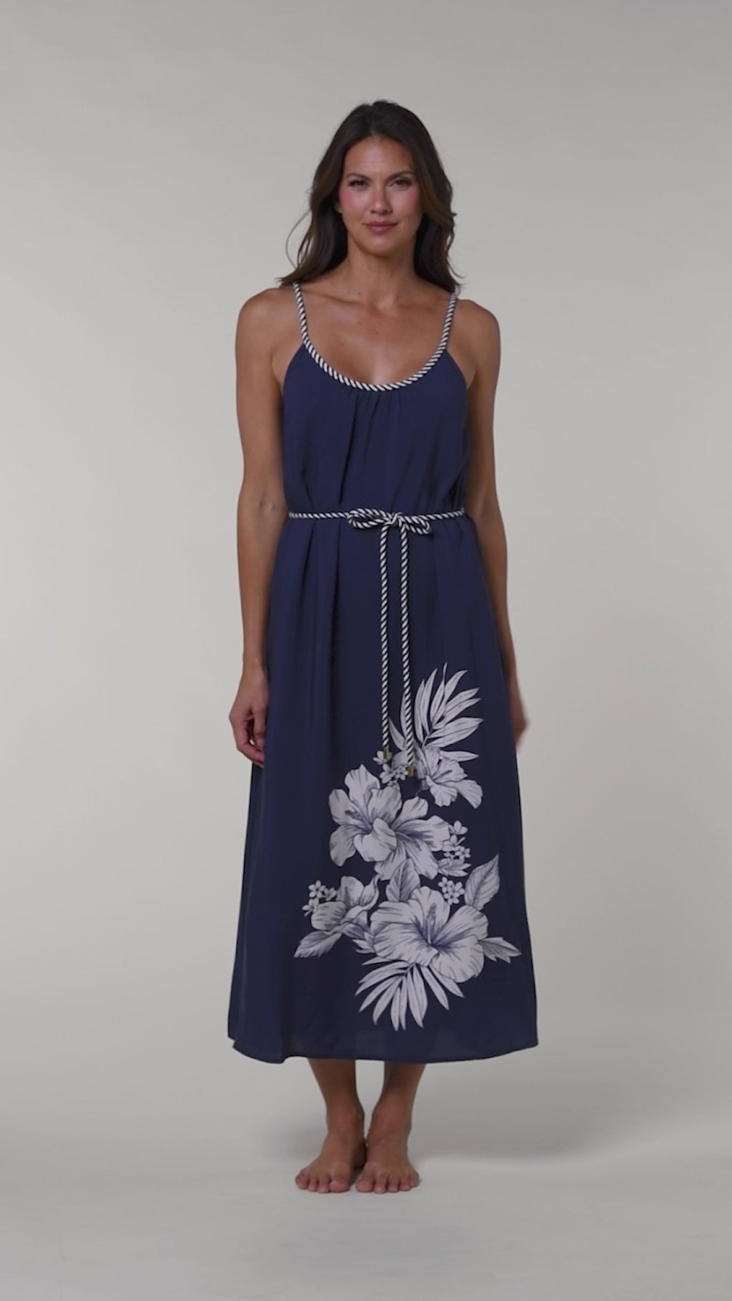 Video of a woman wearing a navy blue cover up dress with floral patterns on a white background