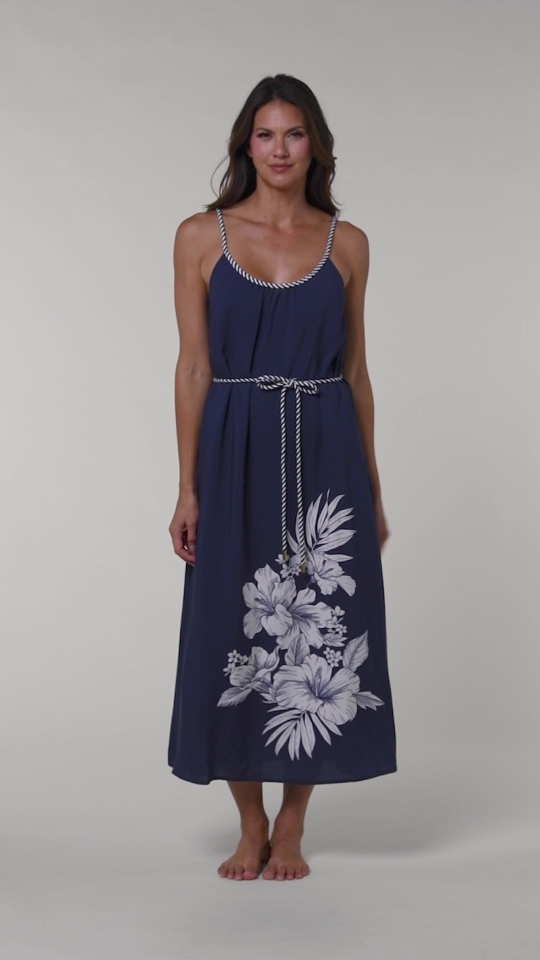 Video of a woman wearing a navy blue cover up dress with floral patterns on a white background