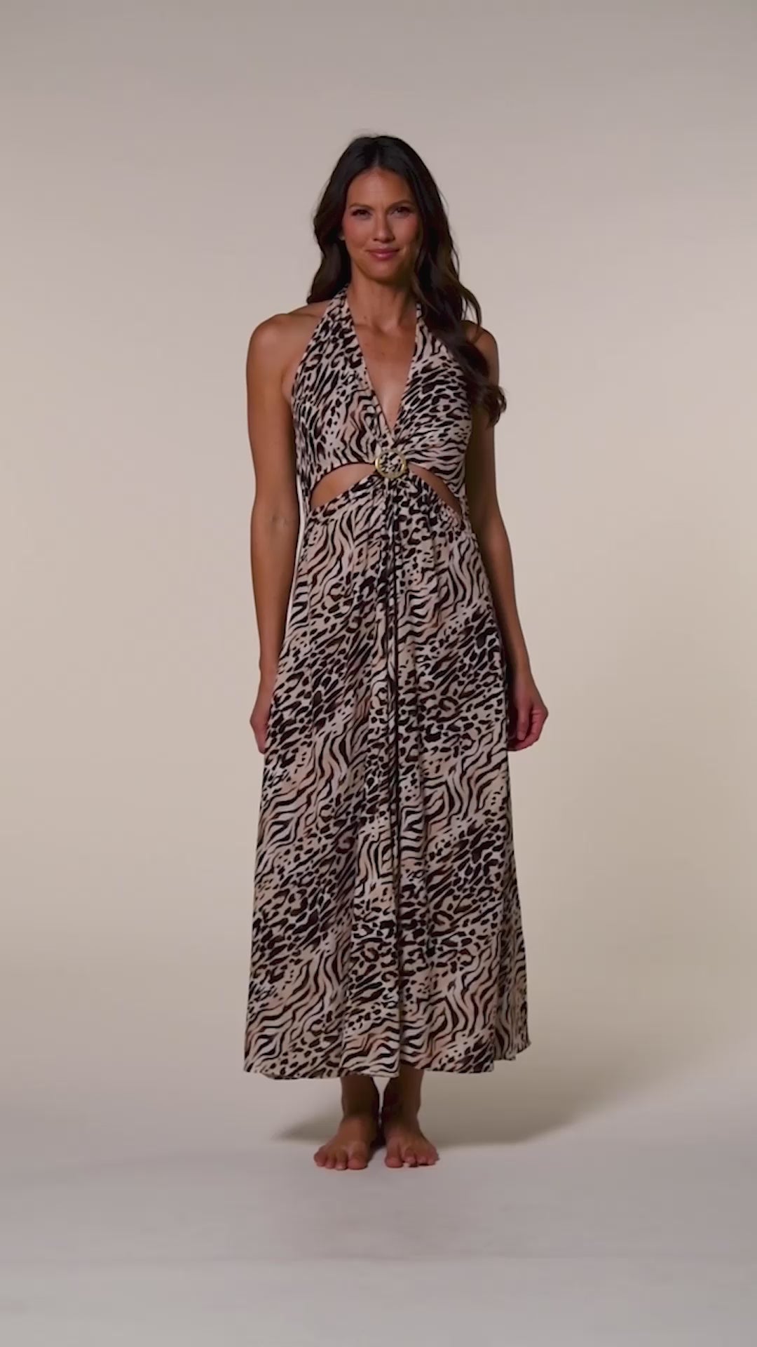 Video of a woman wearing a zebra printed maxi dress cover up against a beige background.