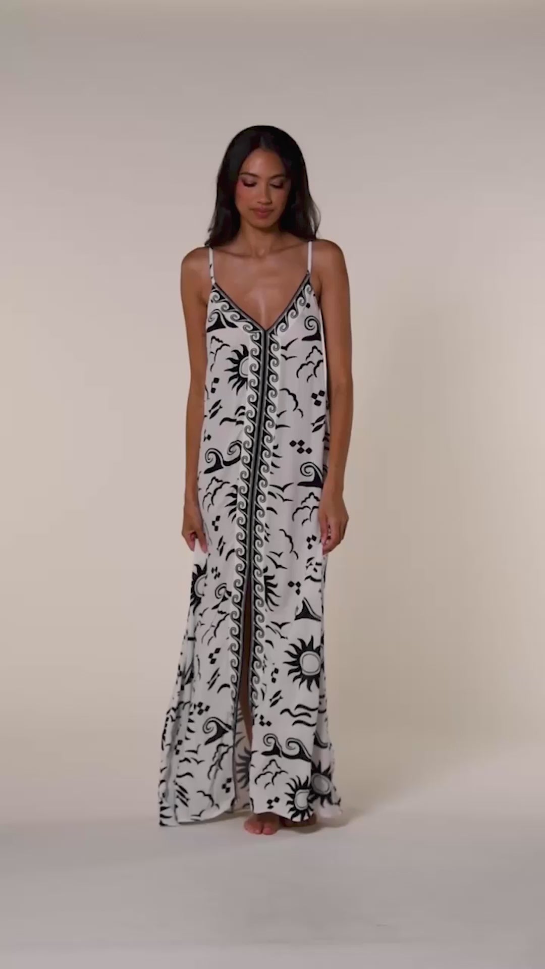 Video of a woman wearing a black and white patterned maxi dress against a beige background.